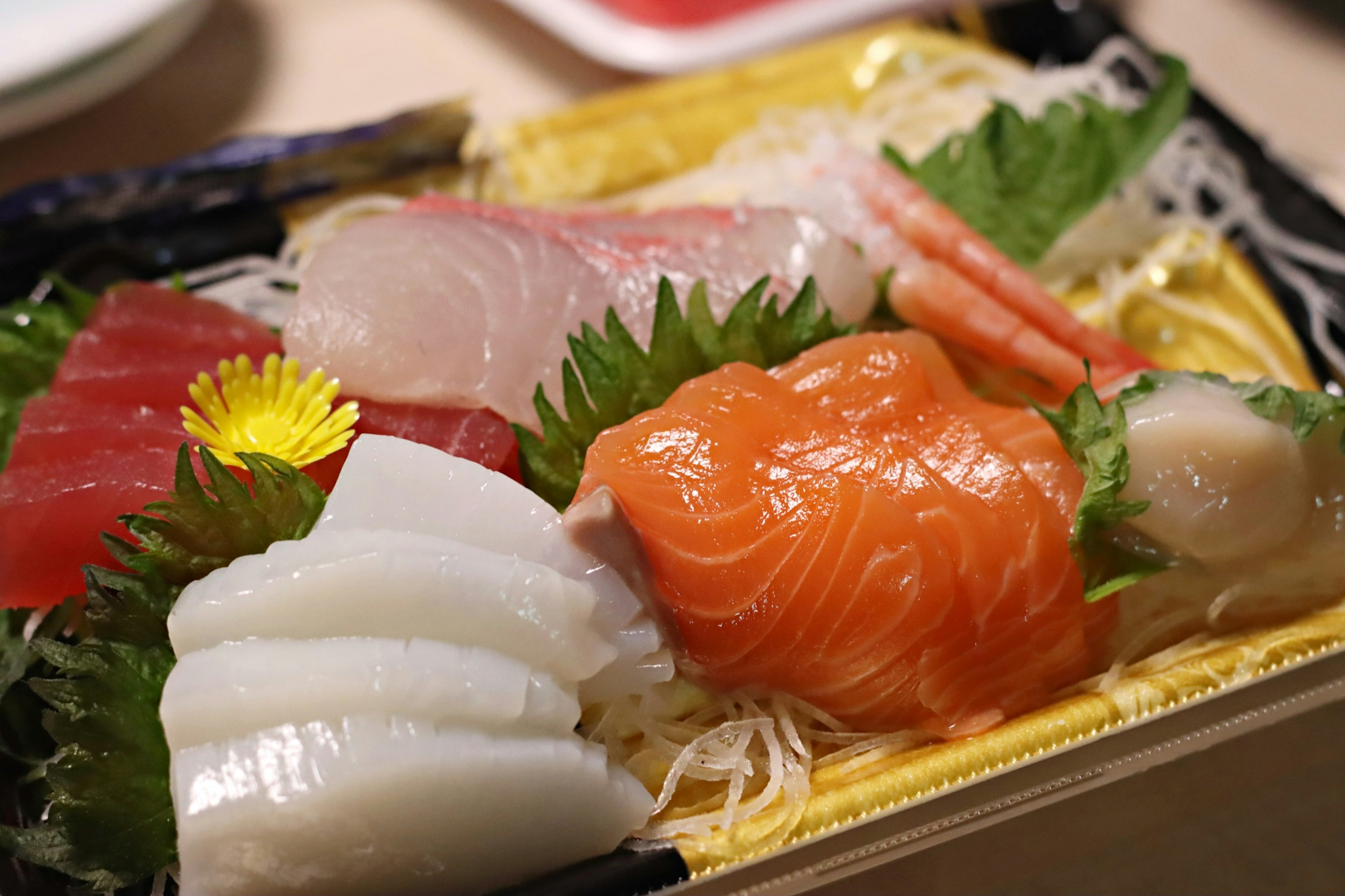 Colorful sashimi platter featuring fresh seafood and garnished with leafy greens