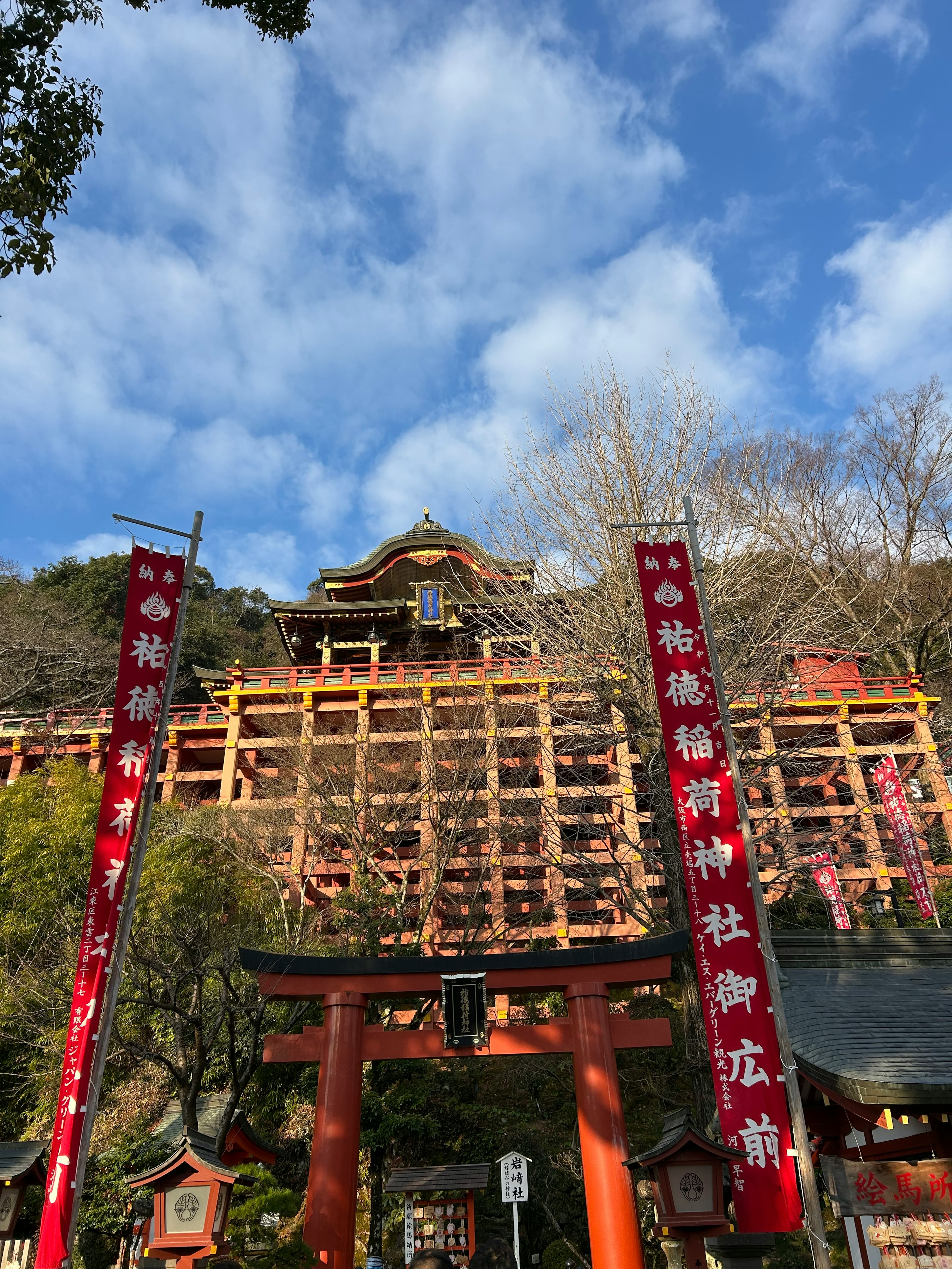 Vista escénica de puertas torii rojas y un edificio de santuario bajo un cielo azul y nubes