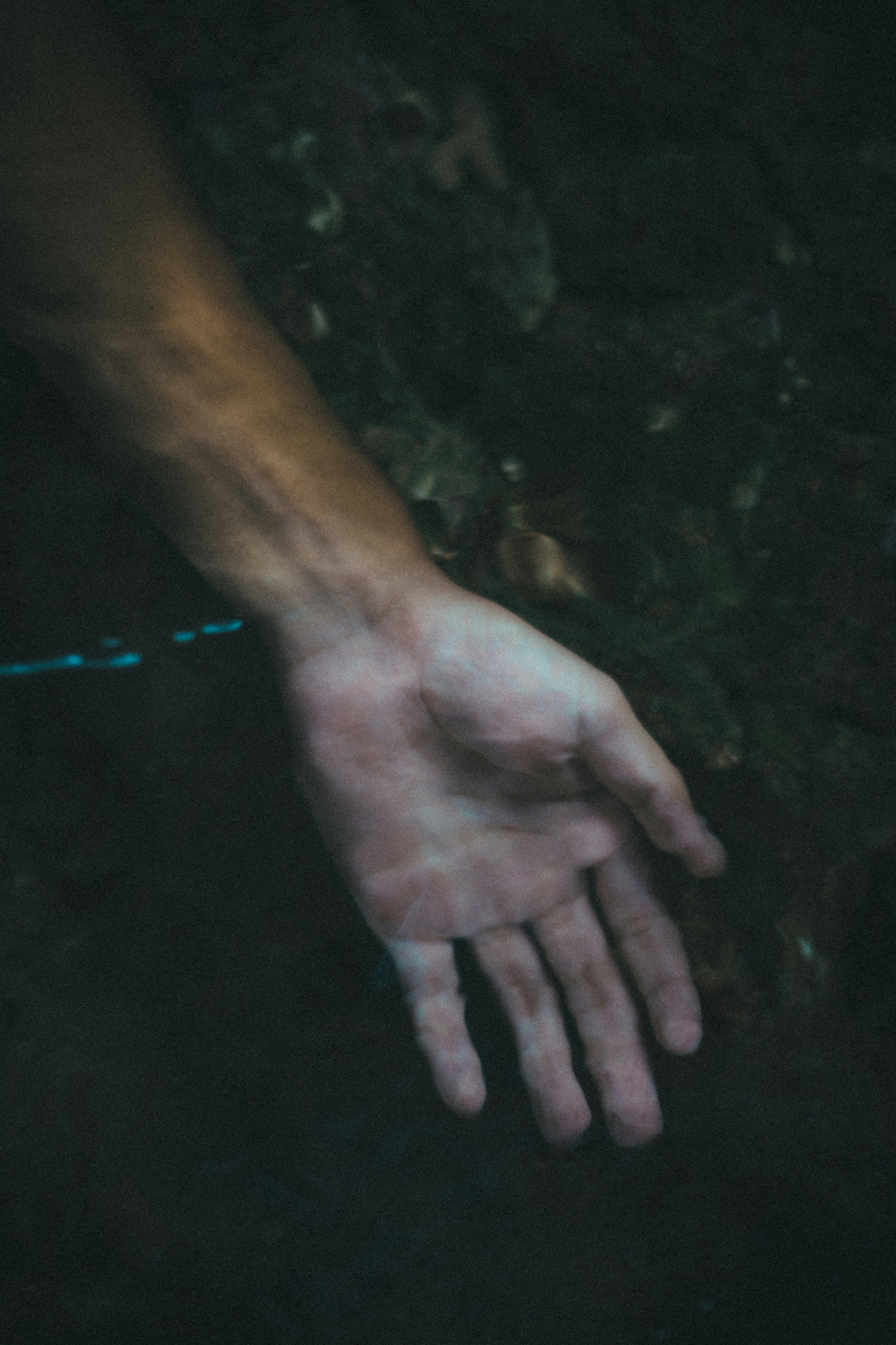 A hand reaching out against a dark background