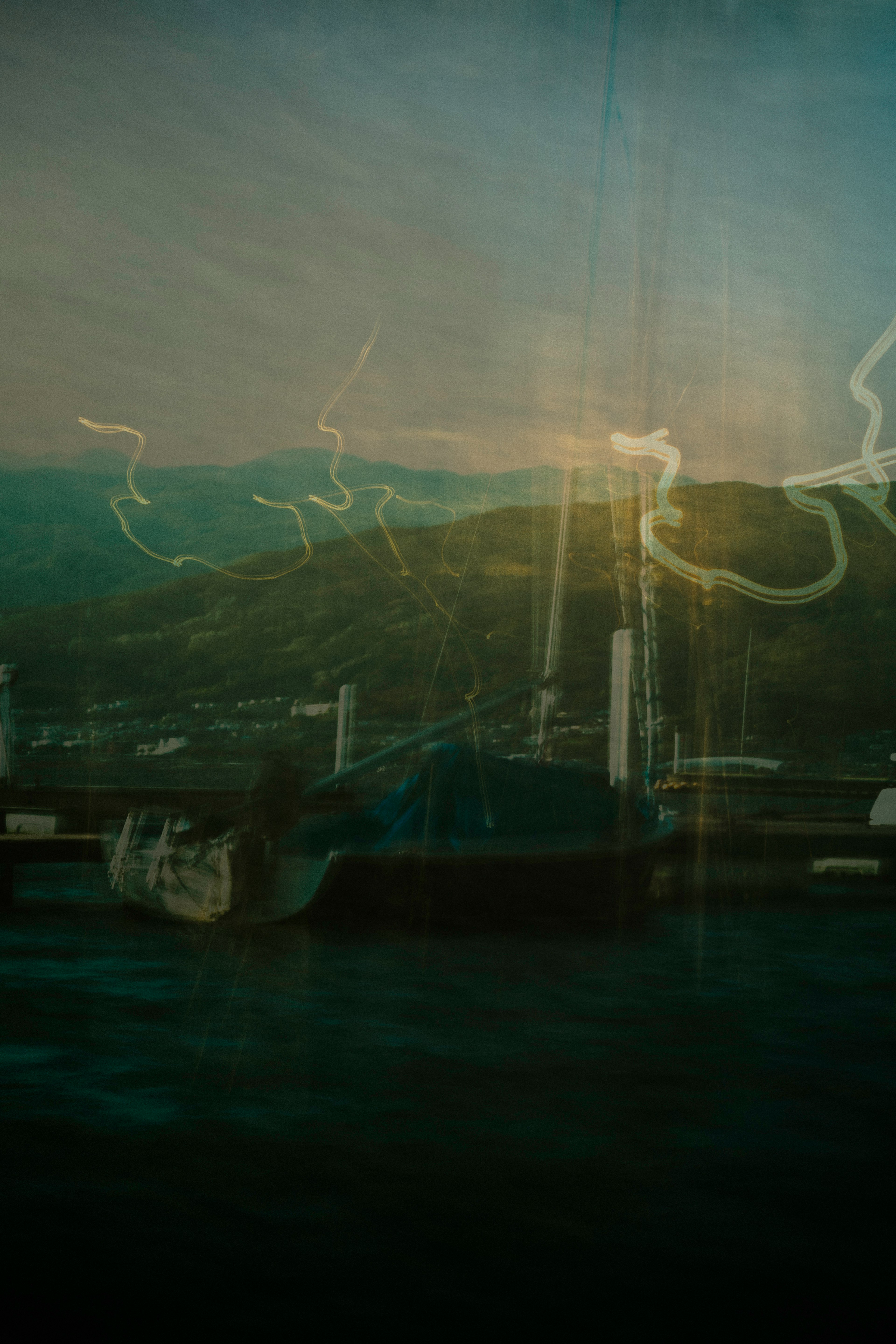 A landscape featuring a blue water surface with a mountain backdrop and light trails