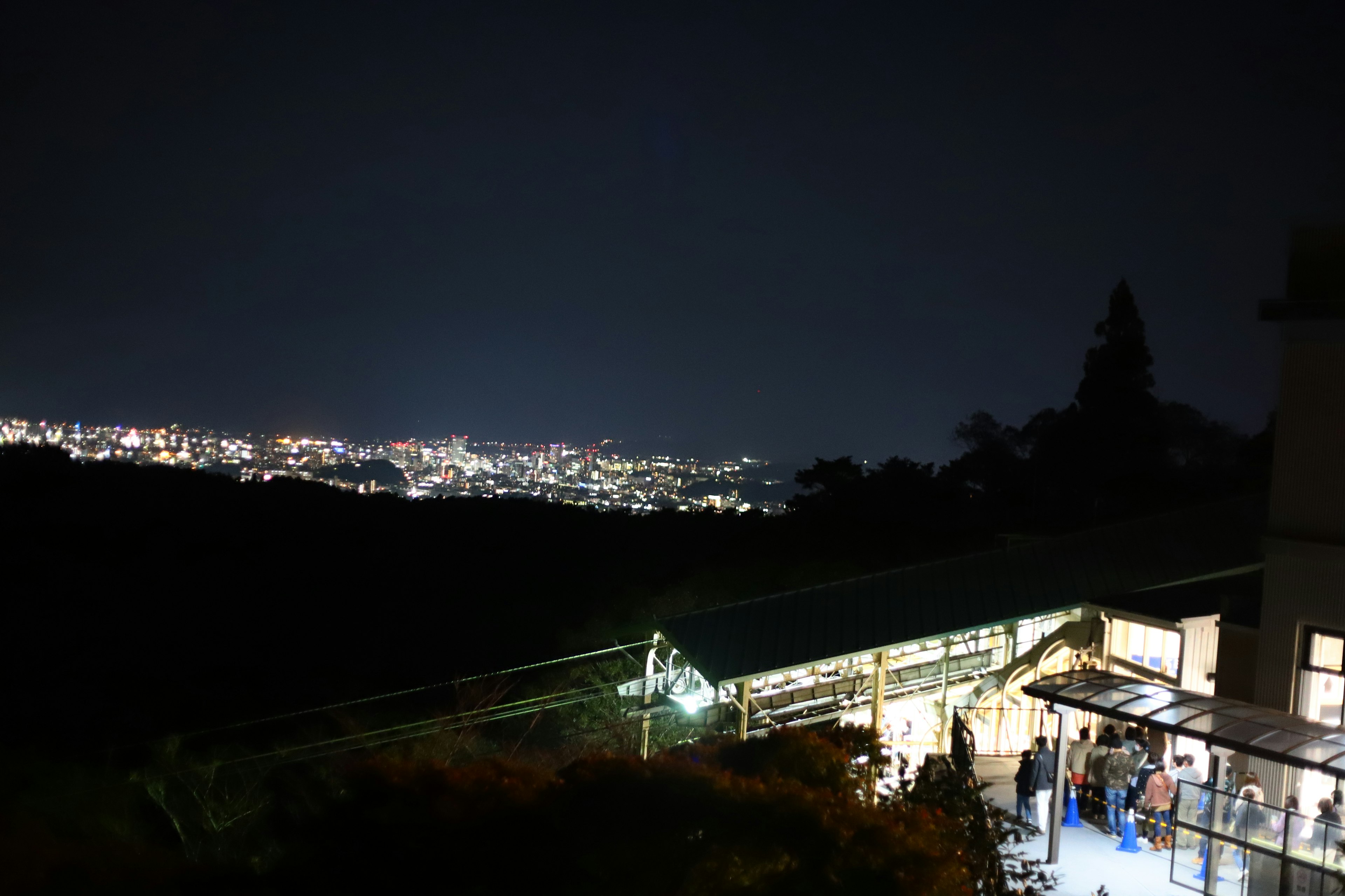 夜景を背景にした駅の外観と周囲の山々