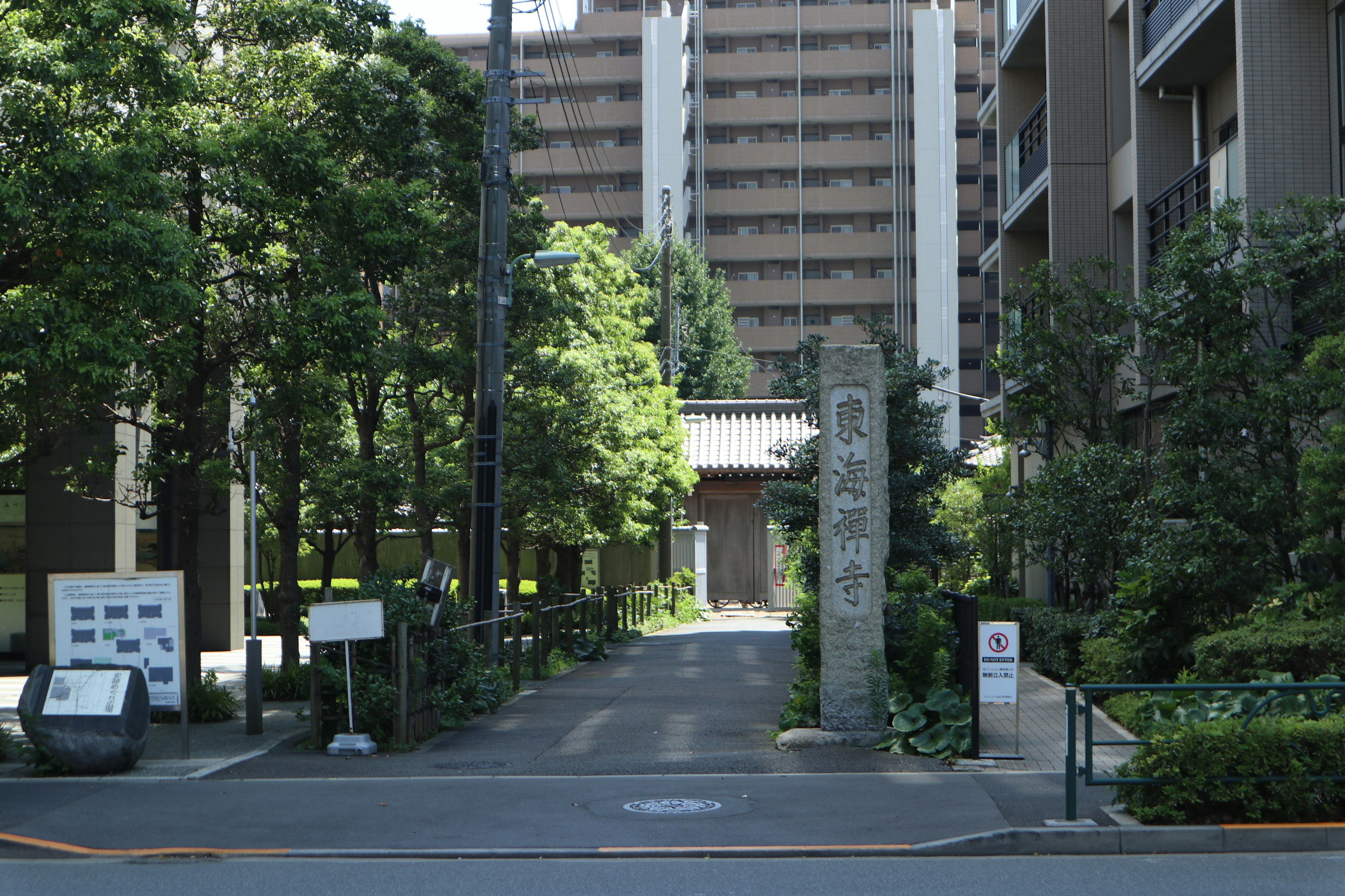 Vista de entrada entre un camino verde y edificios altos