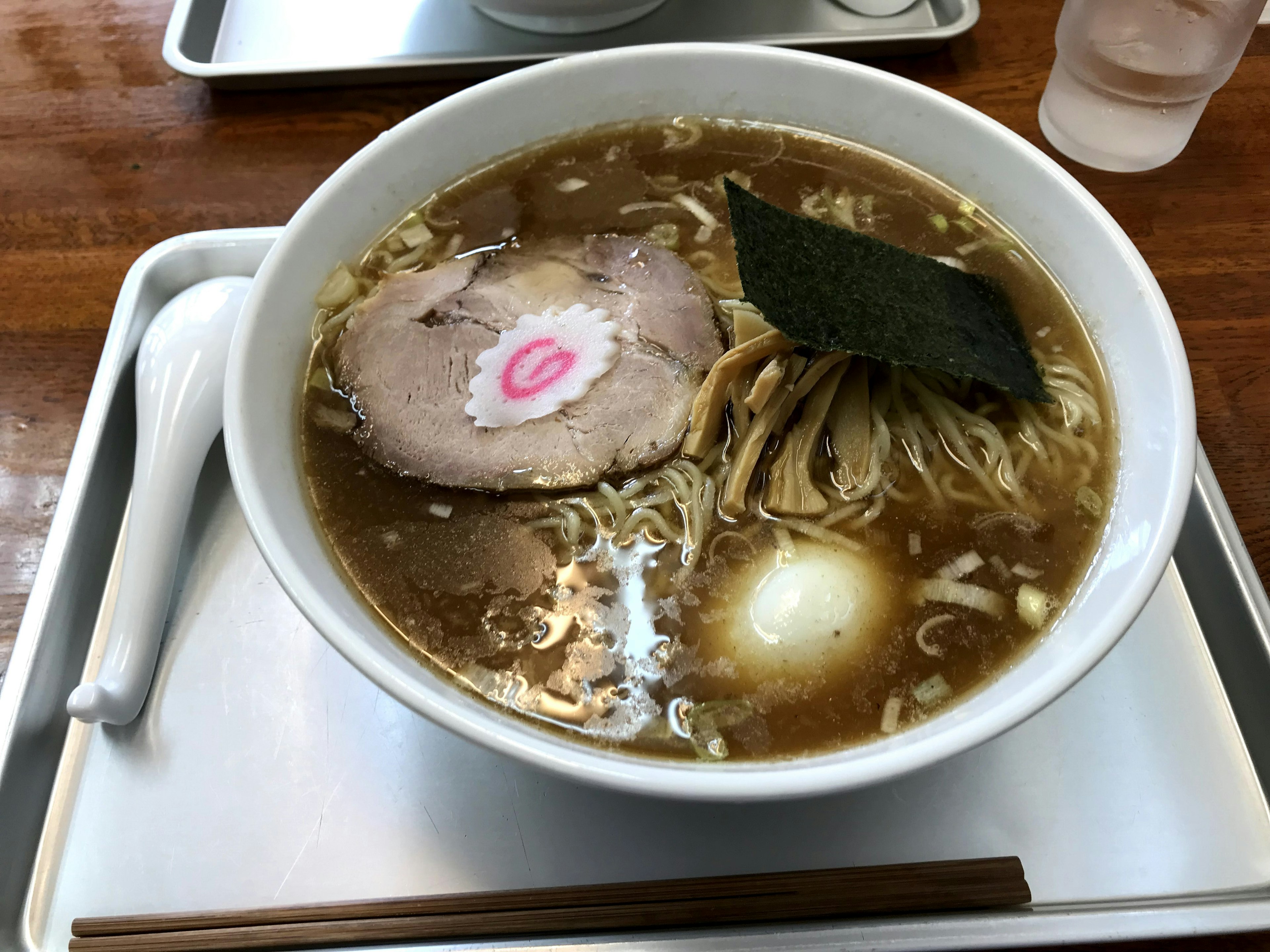 ラーメンのボウルにチャーシューとナルトがトッピングされた美味しそうなスープ