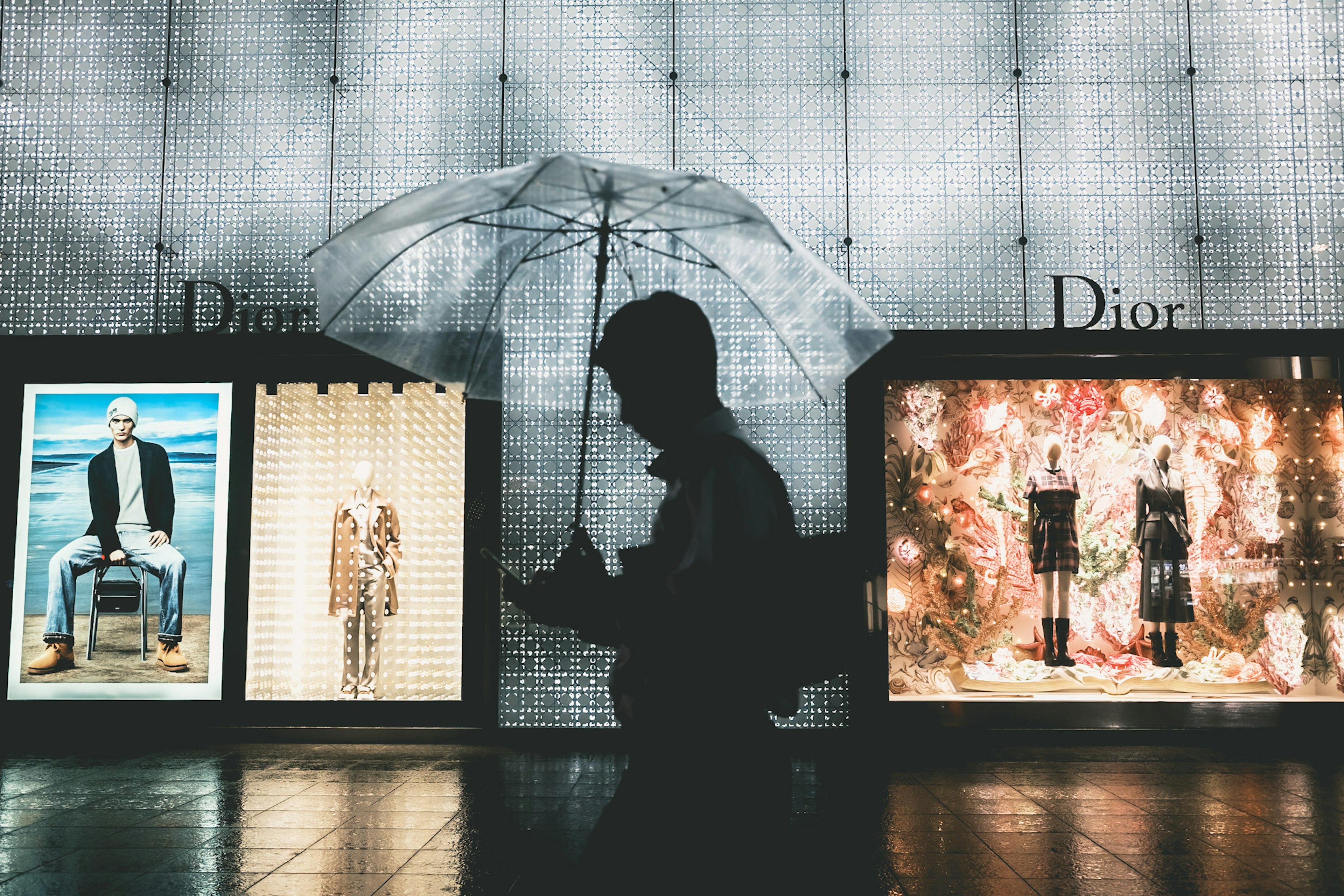 Silhouette holding an umbrella with Dior window displays