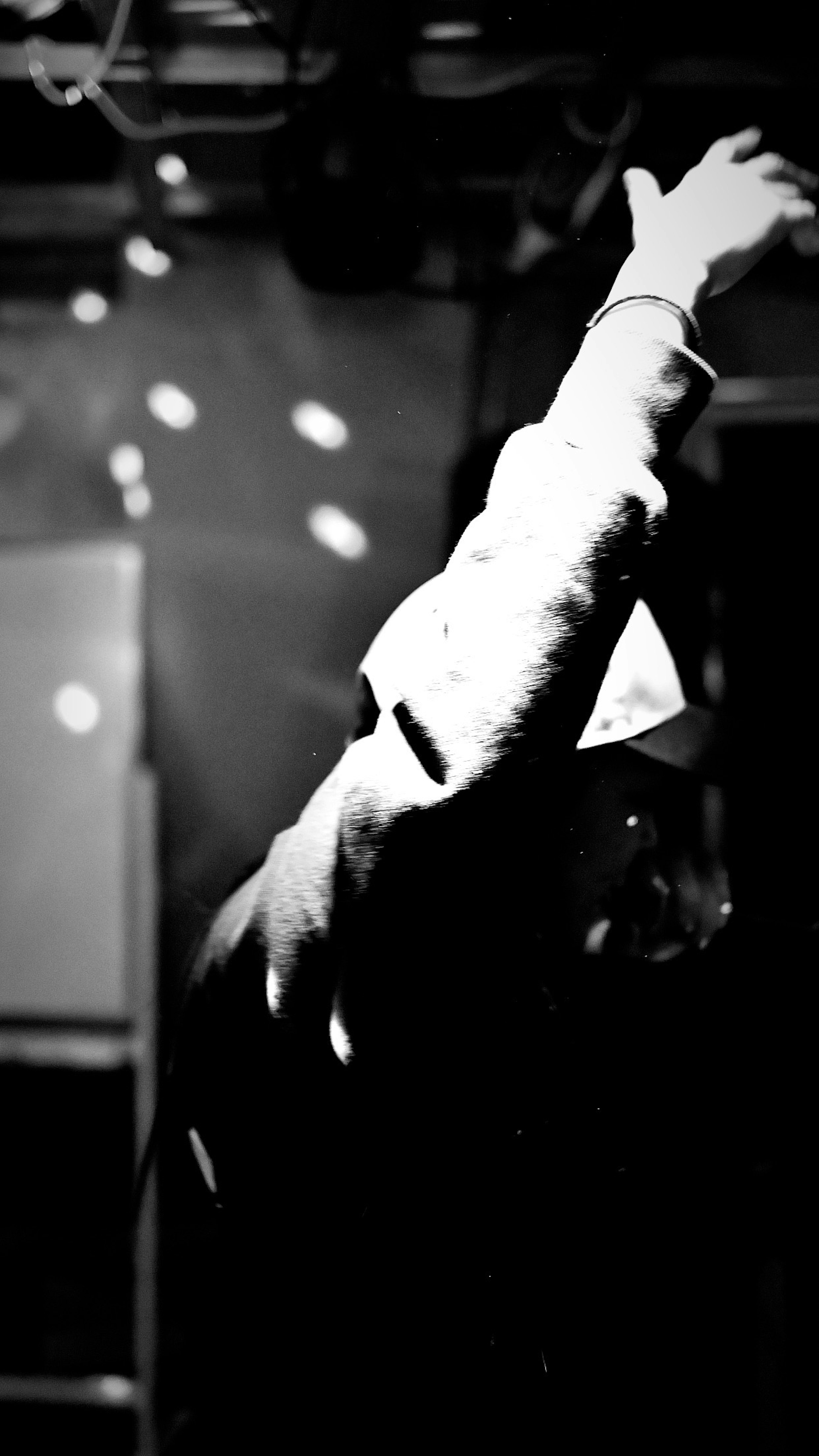 Silhouette of a person raising their hand against a black and white background Light spots scattered around