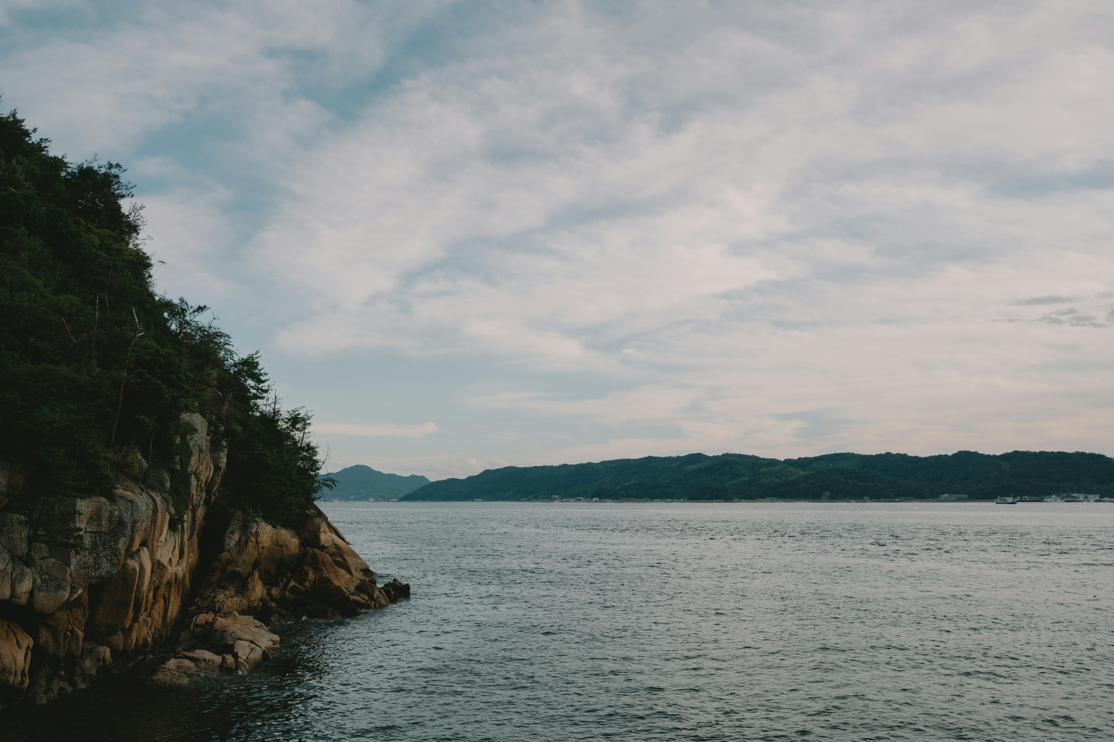 Calm sea and mountain view rocky shoreline with cloudy sky