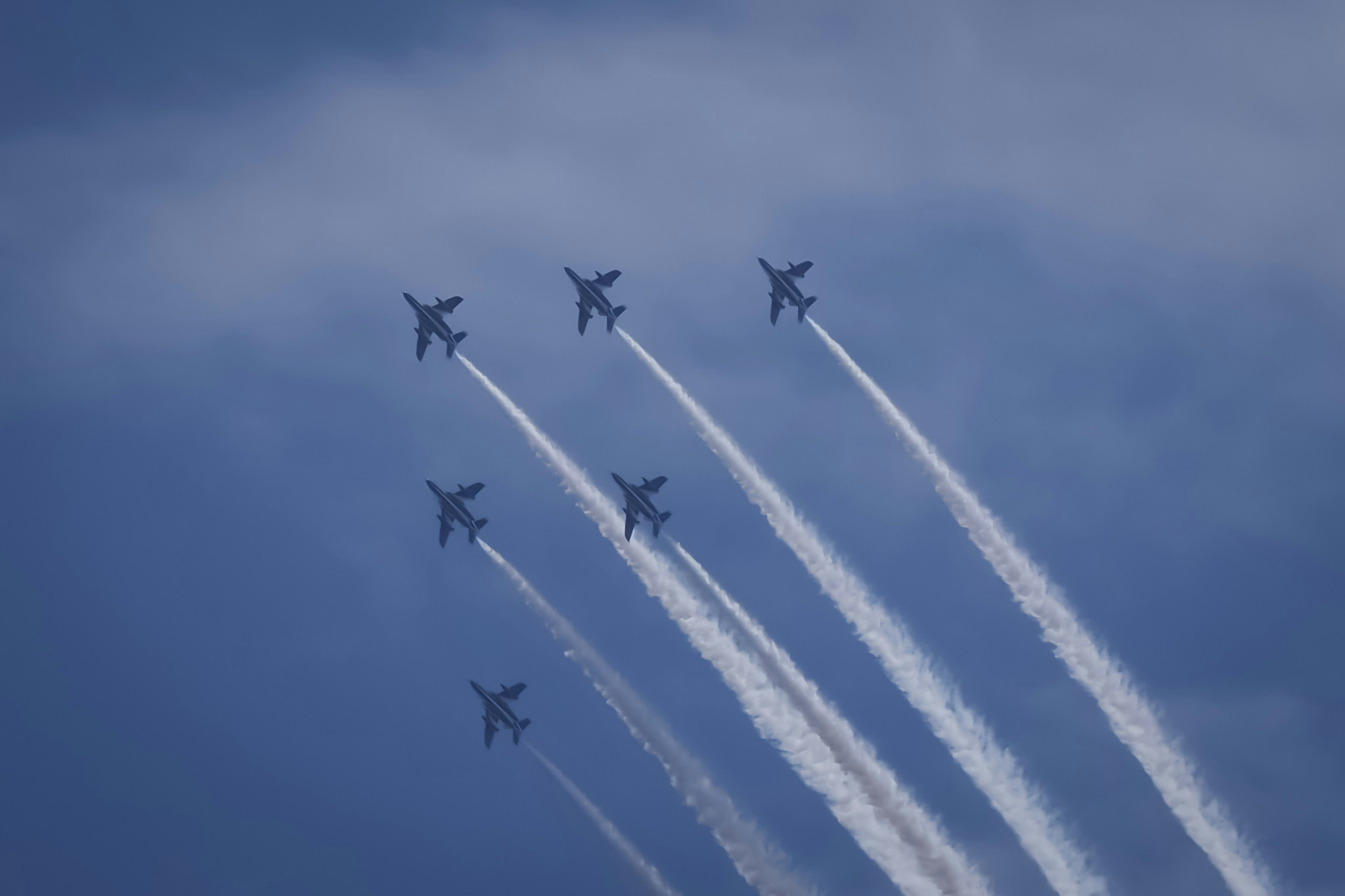 青空に飛ぶ6機の戦闘機が白い飛行機雲を残している