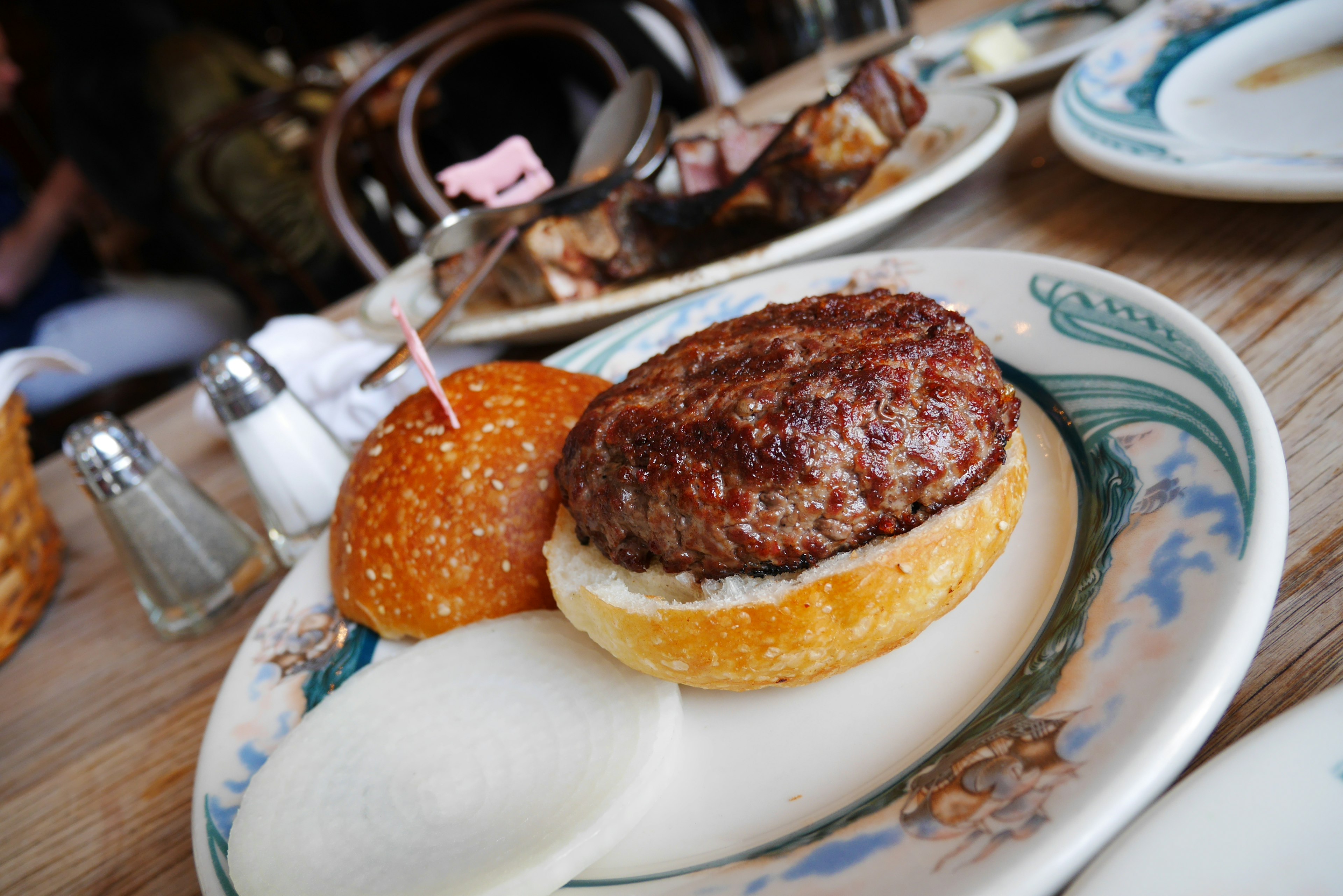 Carne de hamburguesa gruesa sobre un pan suave con encurtidos al lado