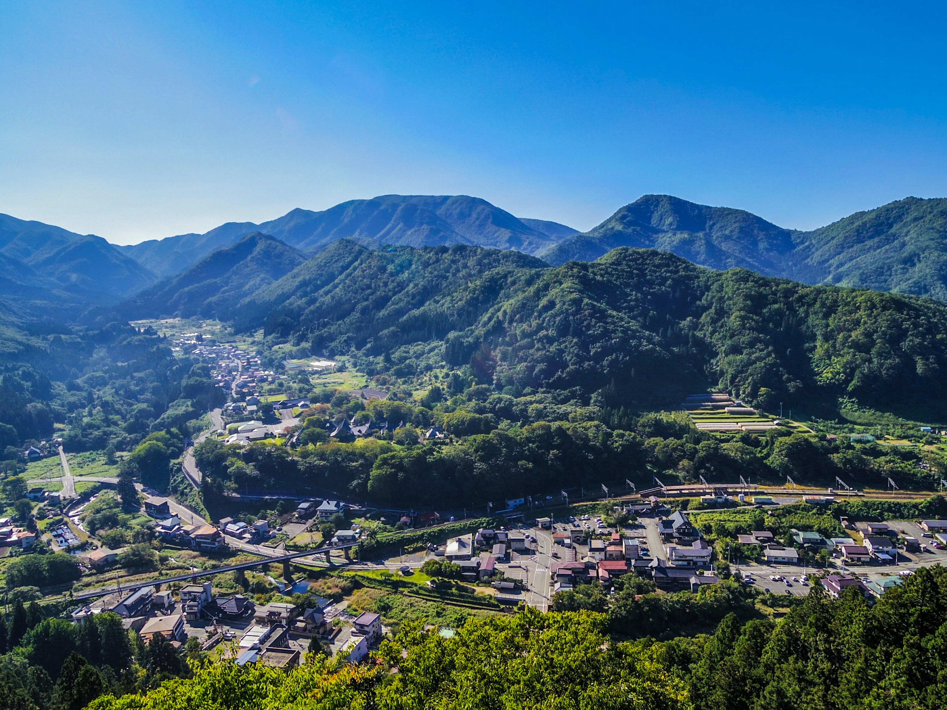 Ruhige Dorfansicht umgeben von Bergen und blauem Himmel