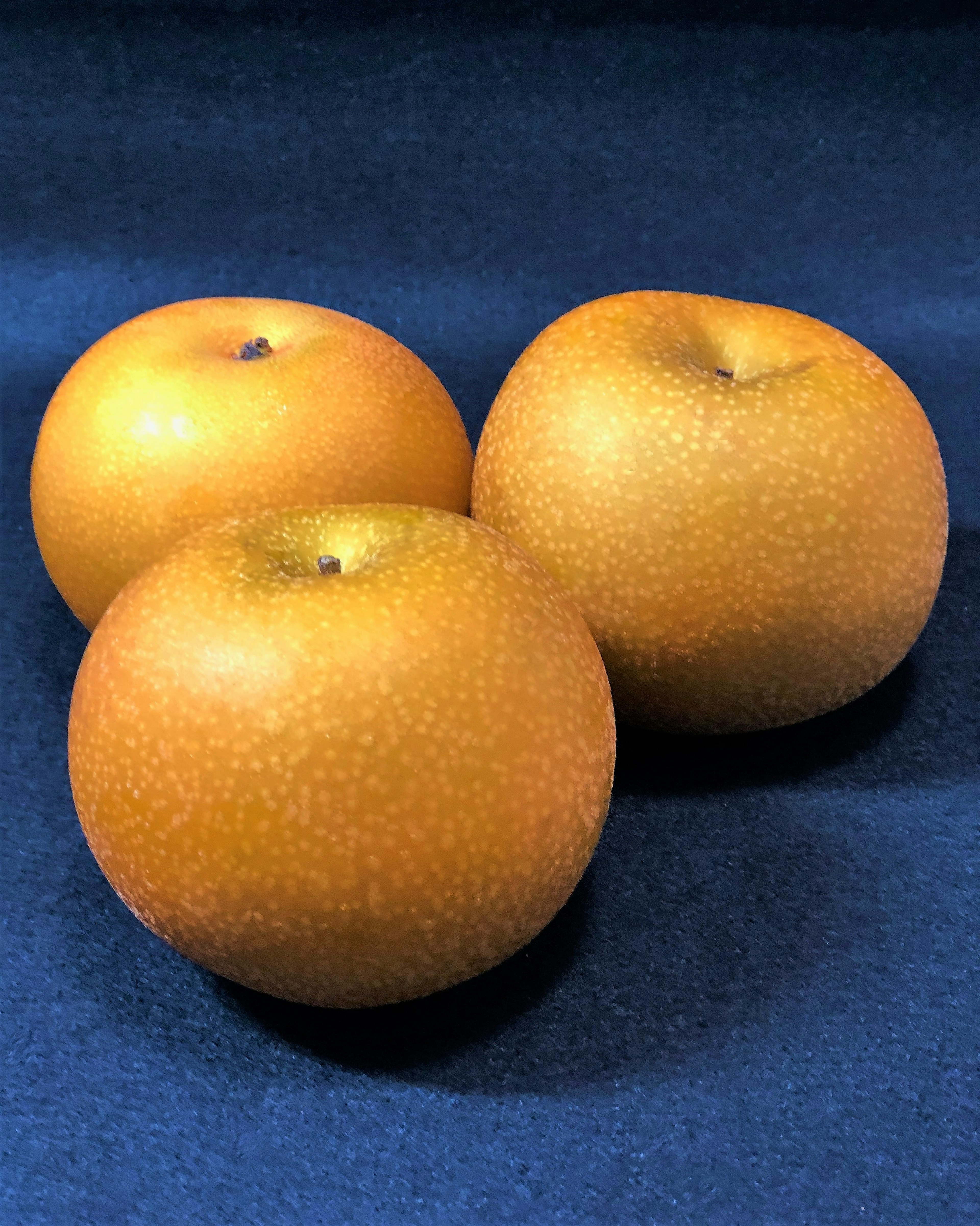 Trois belles poires orange placées sur un fond en tissu bleu