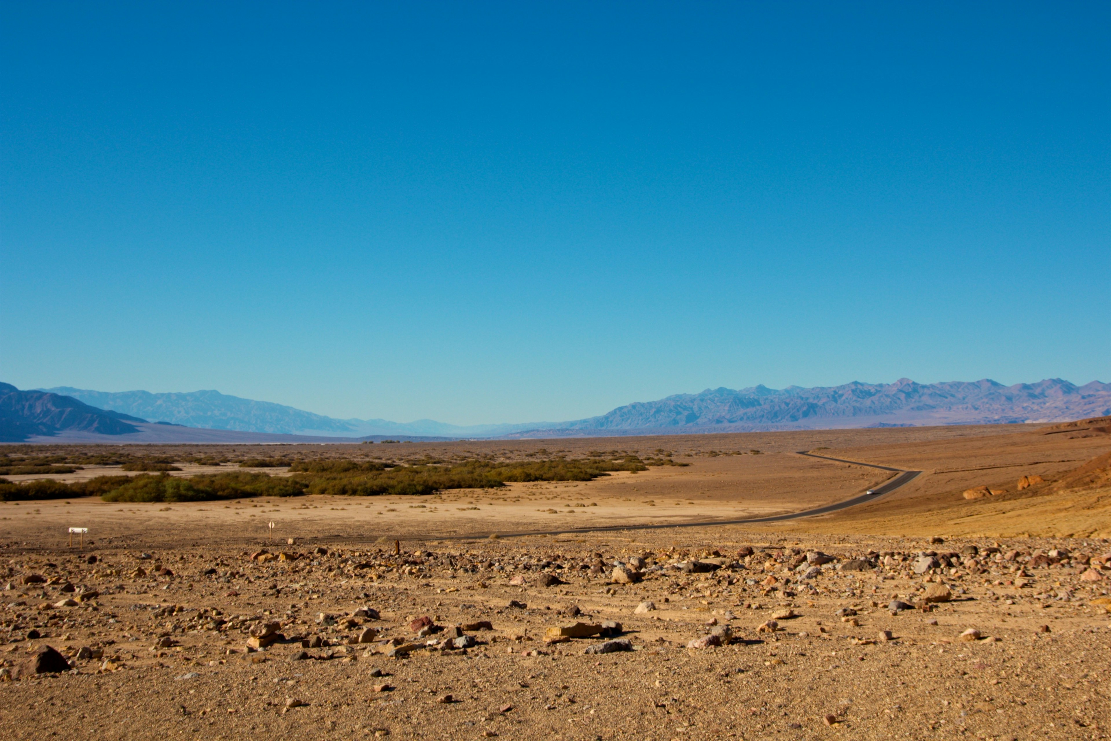 Vast desert landscape under a blue sky with distant mountains