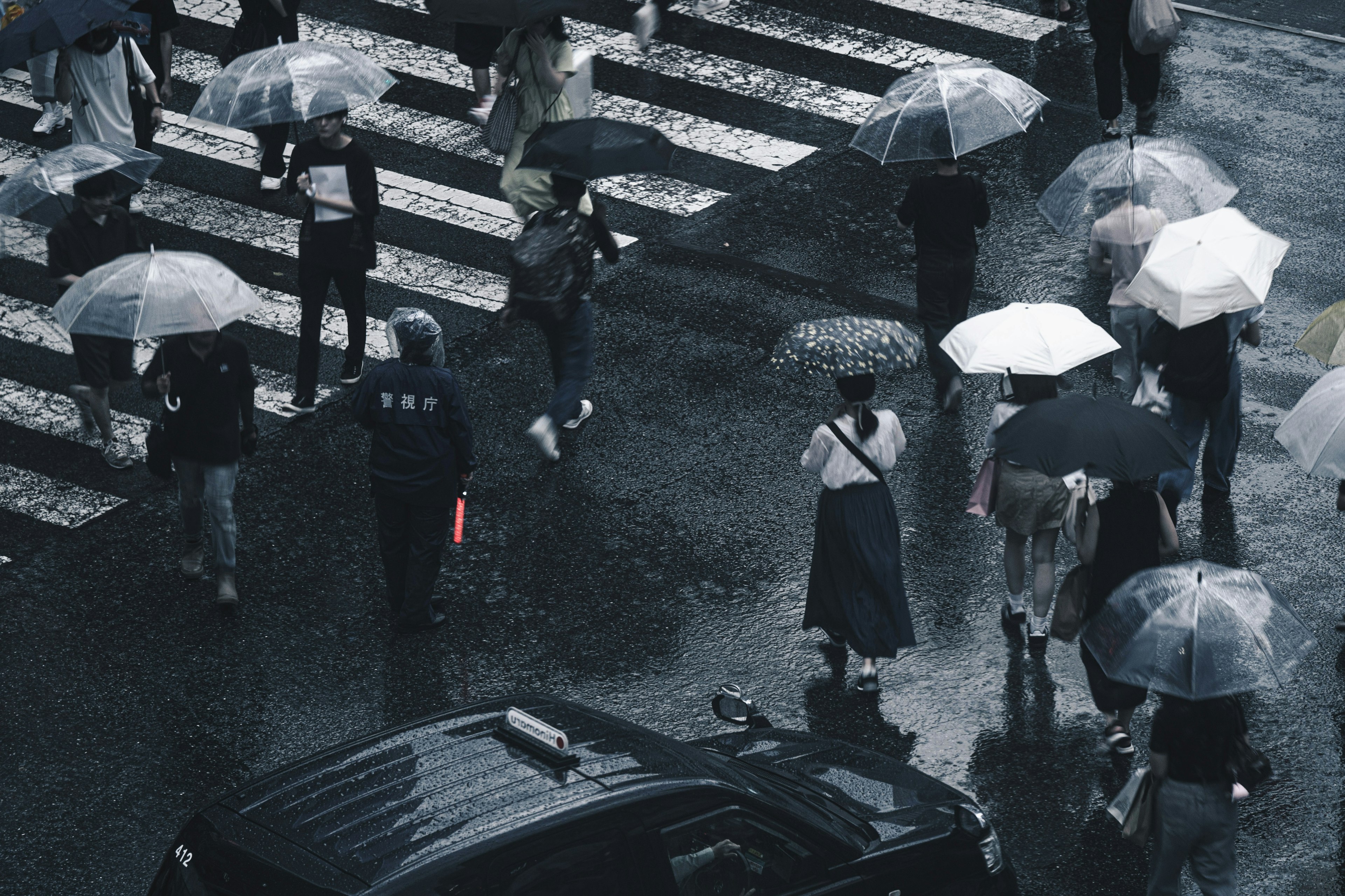 Menschen mit Regenschirmen überqueren eine Straße im Regen