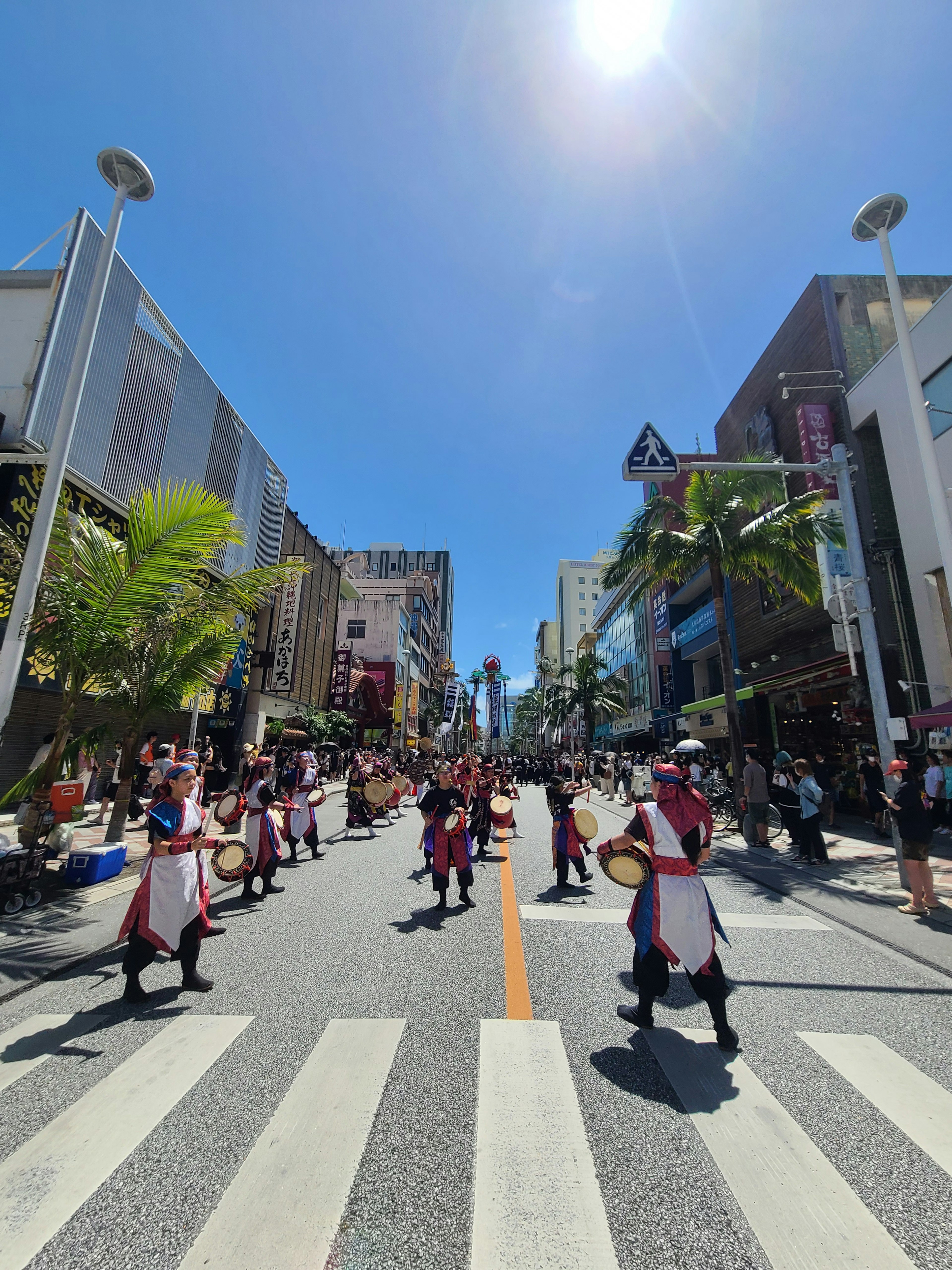 青空の下で行進する伝統的な衣装の人々がいる祭りの風景