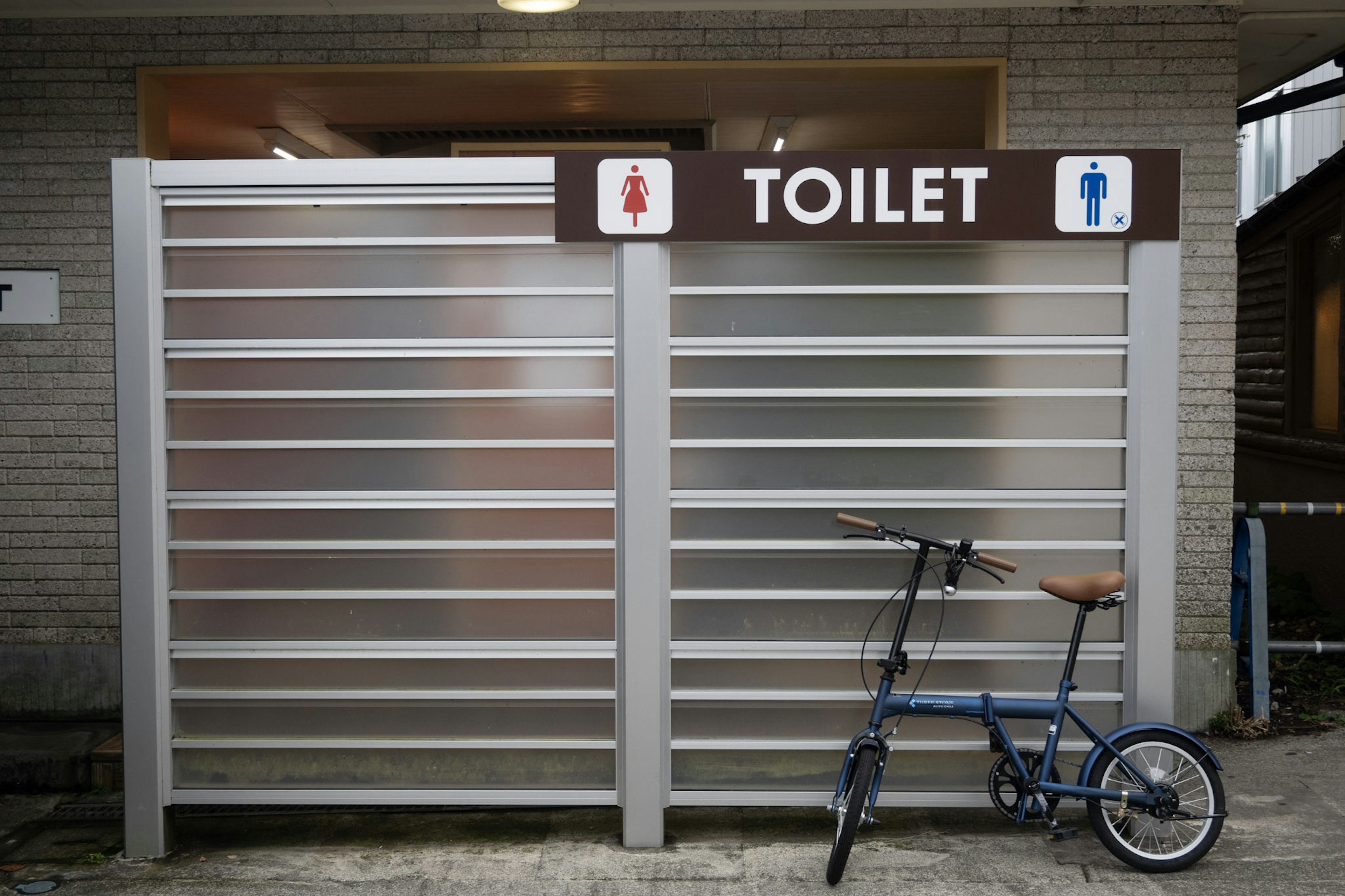 Metallwand mit Toilettenschild und einem Fahrrad