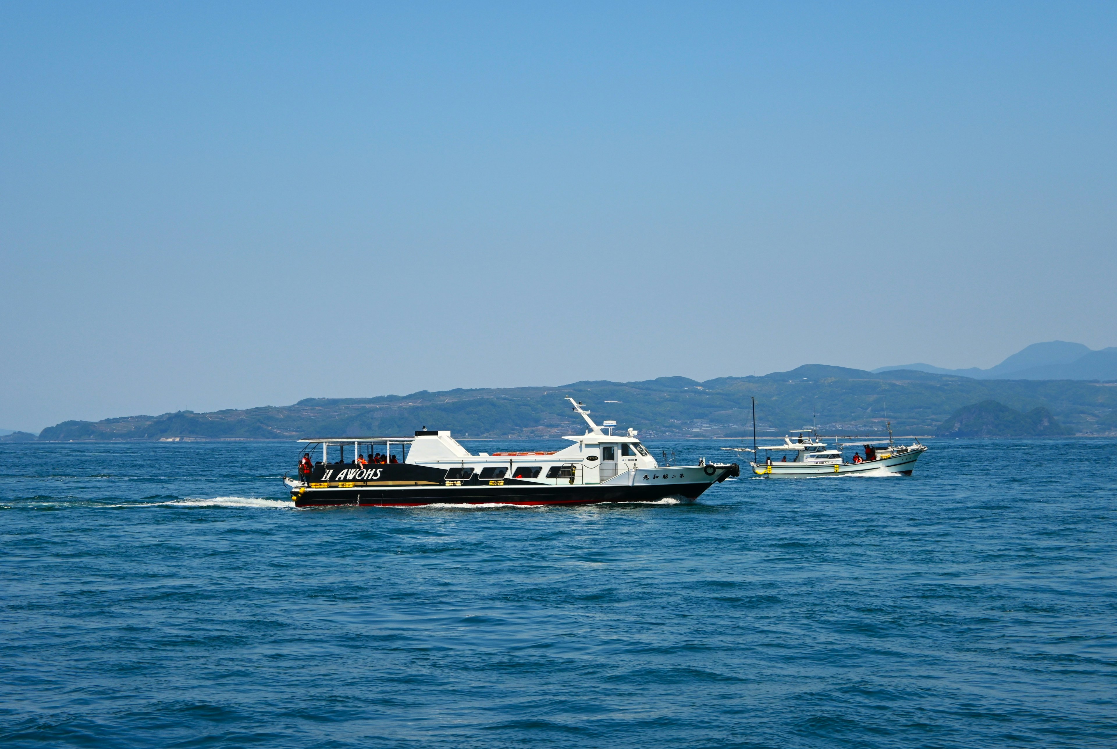 Two boats on a blue sea with mountains in the background