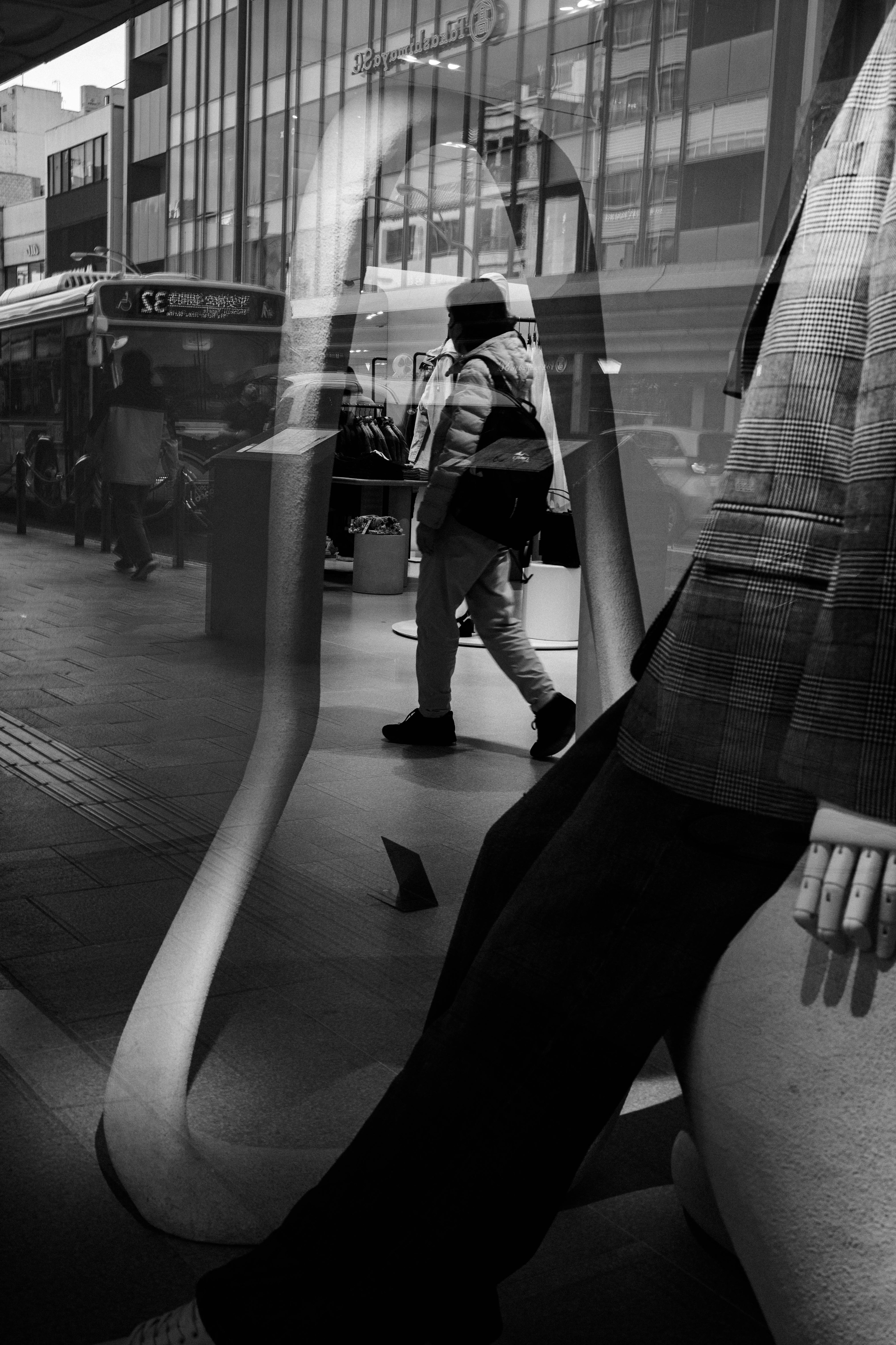 Scène de rue en noir et blanc reflétant une personne et un mannequin en contraste