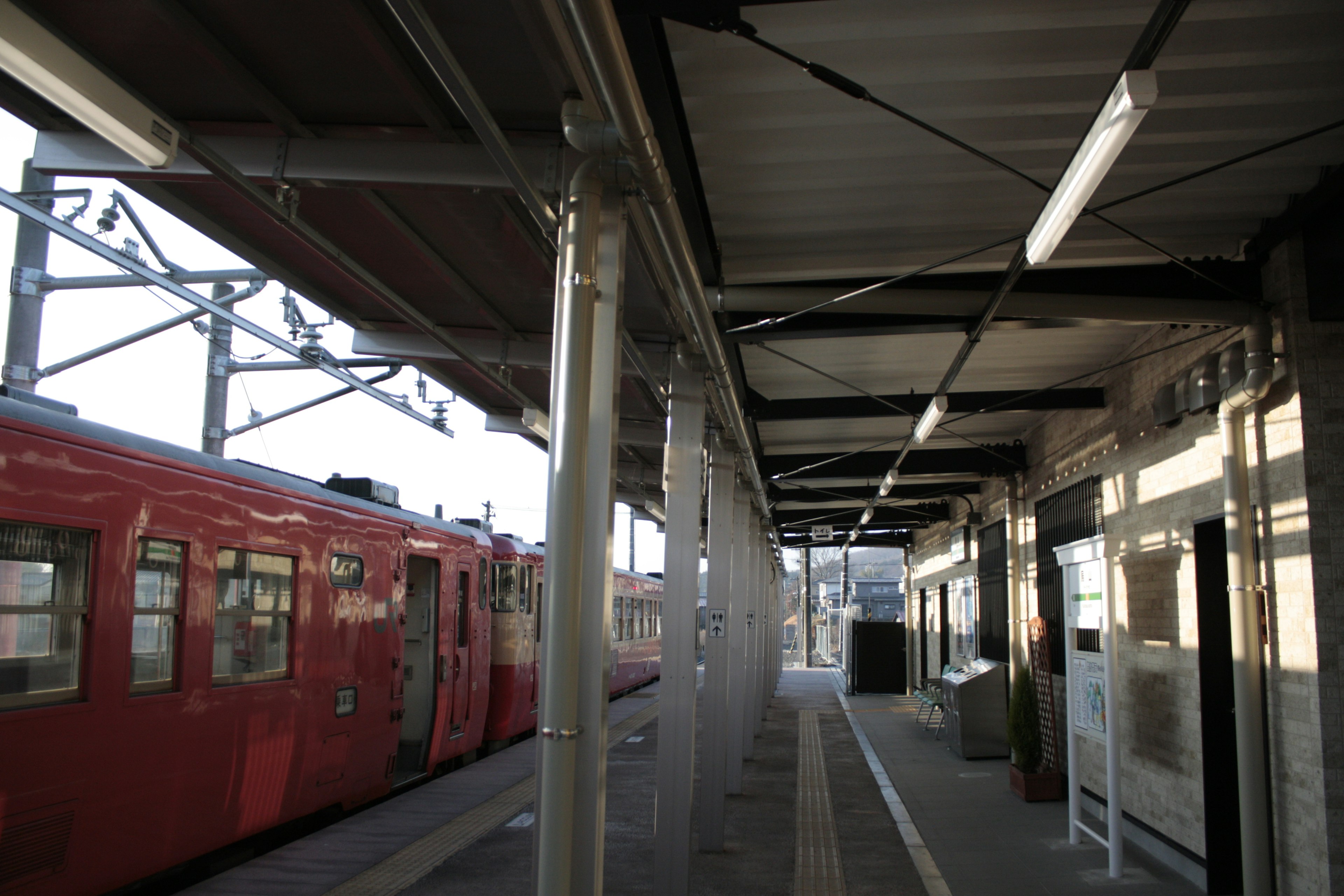 赤い電車が停車中の駅のプラットフォームの風景