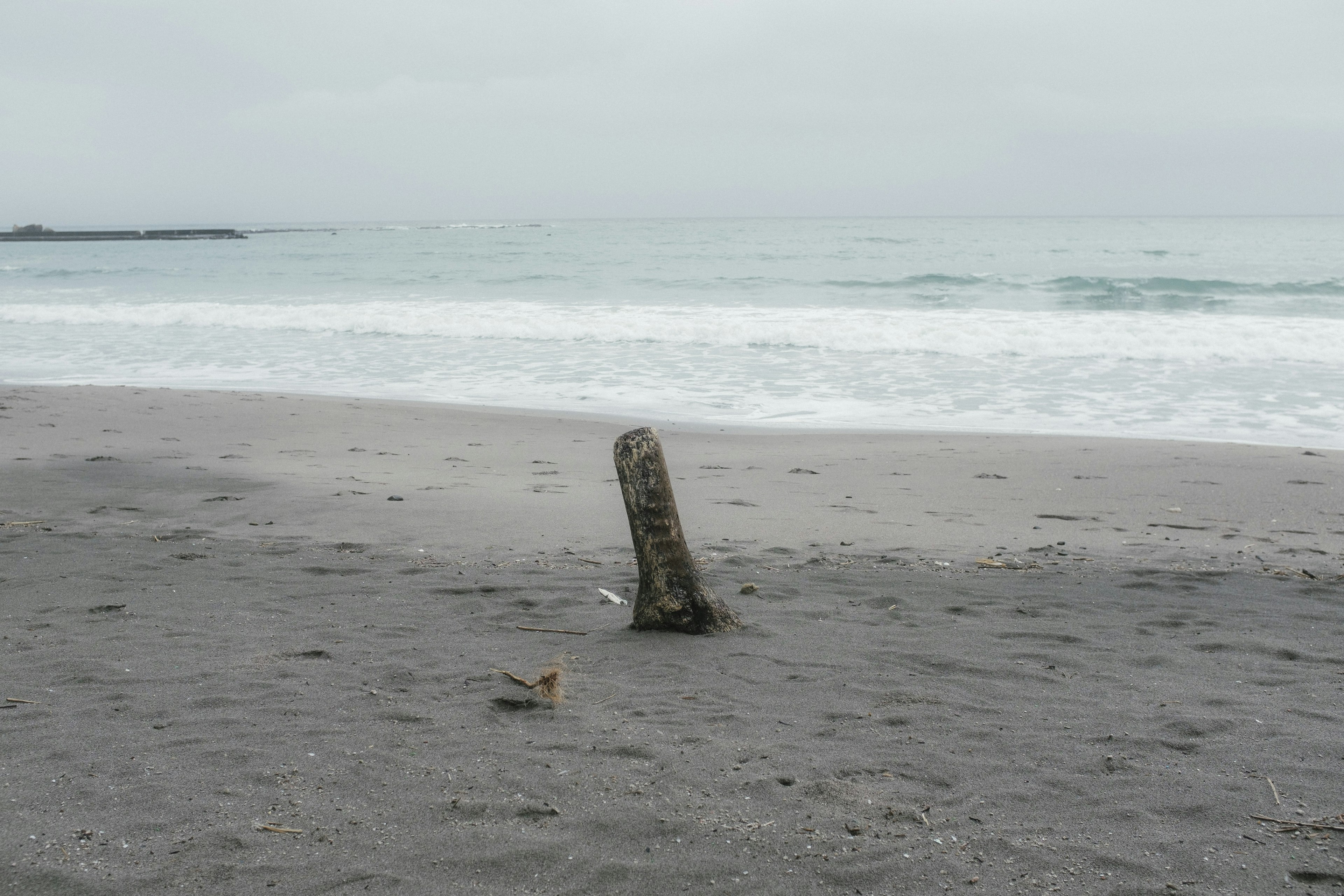 Ein Steinsäule am Strand mit Wellen im Hintergrund