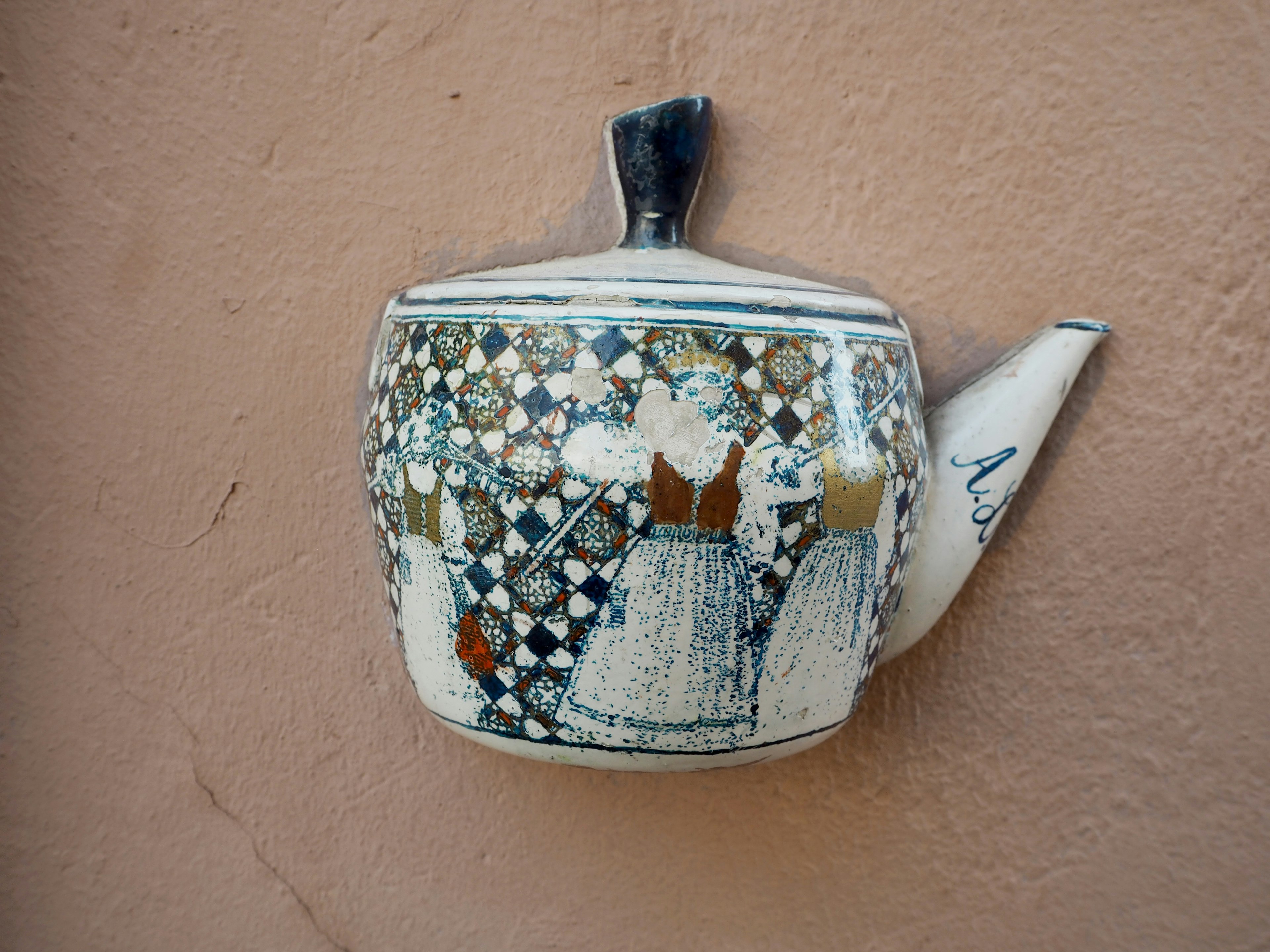 Decorative ceramic teapot with unique design hanging on a wall