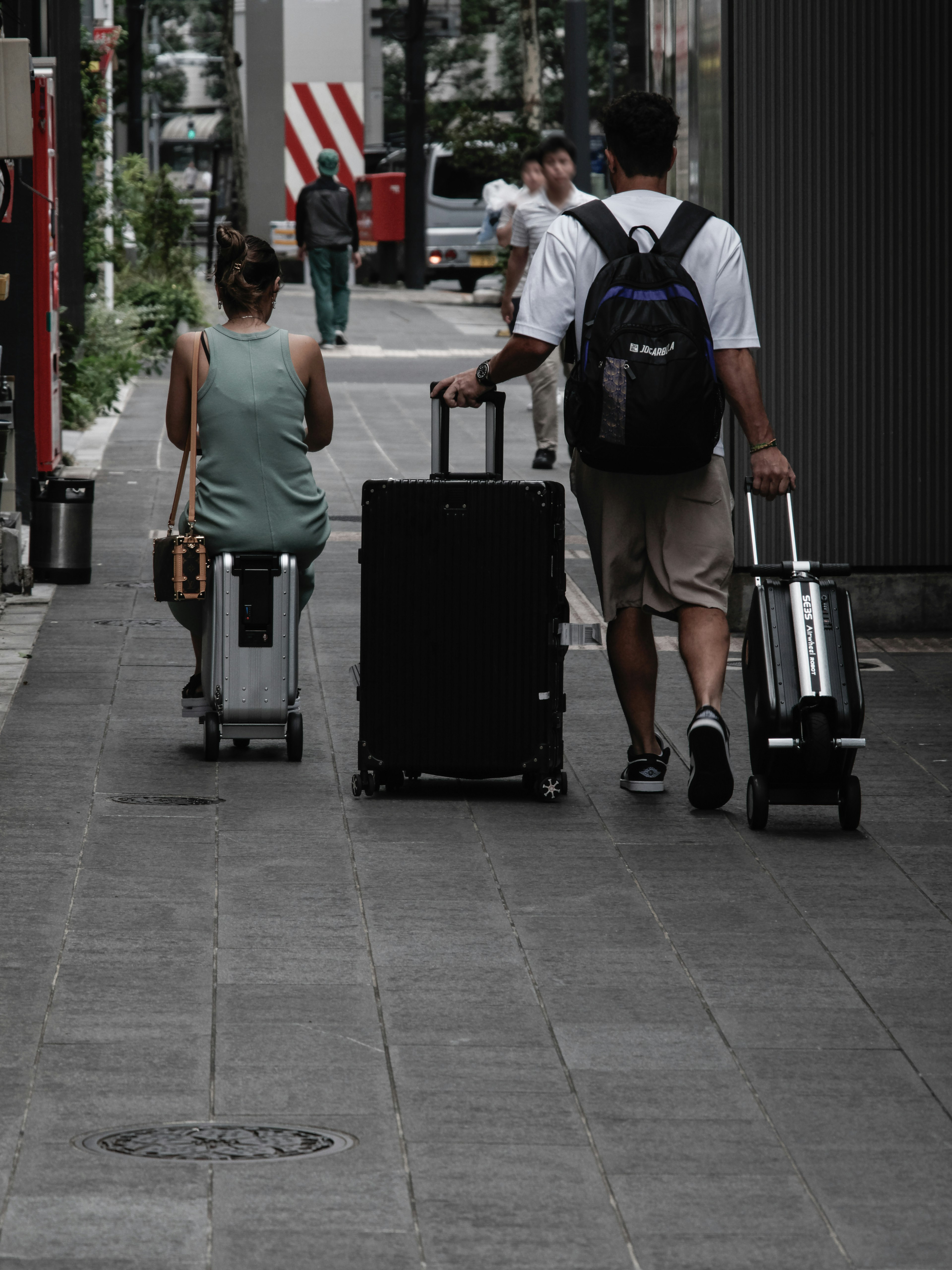 Due viaggiatori che camminano per strada con i loro bagagli