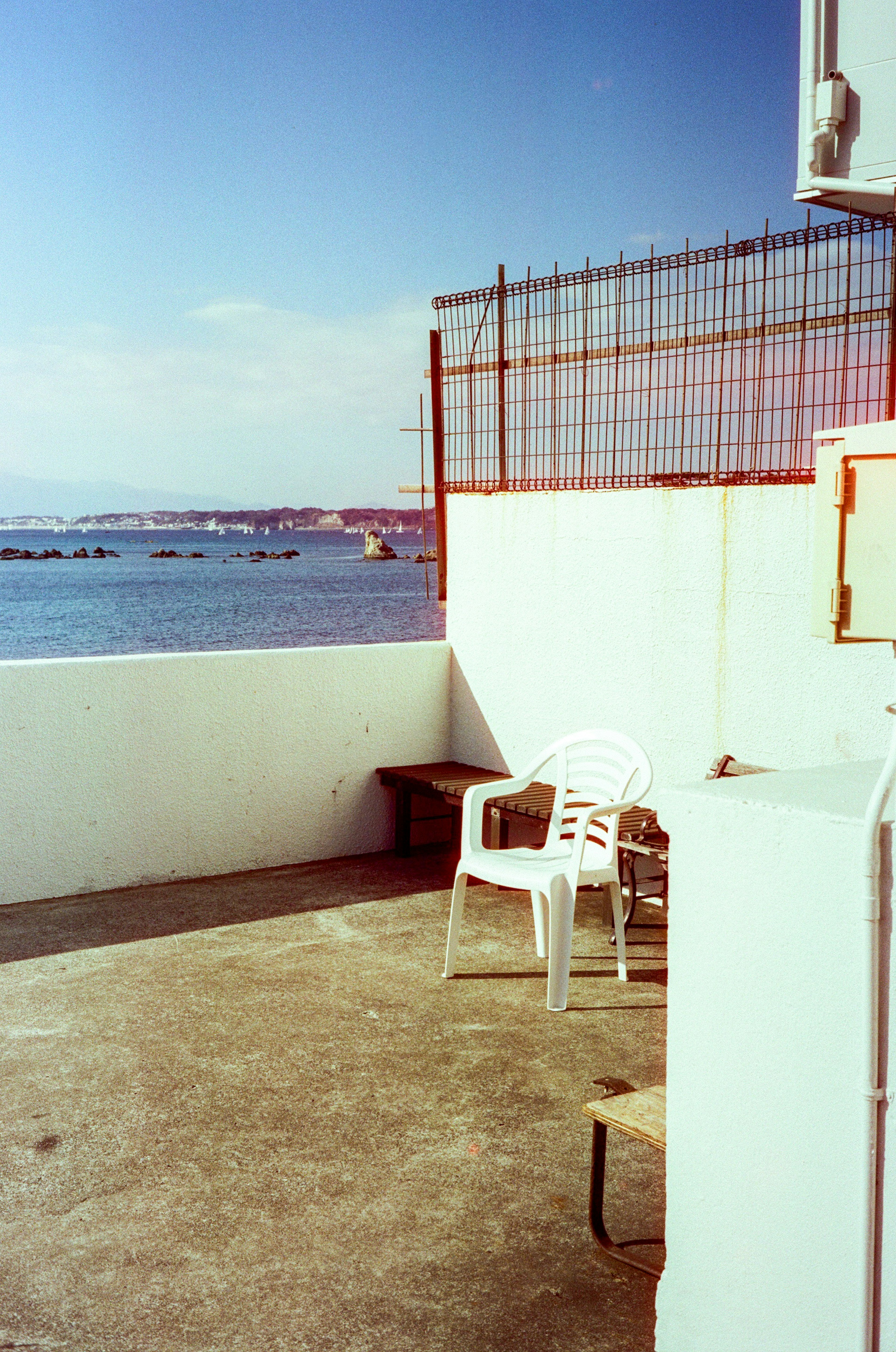 Una silla de plástico blanca en una terraza con vista al mar