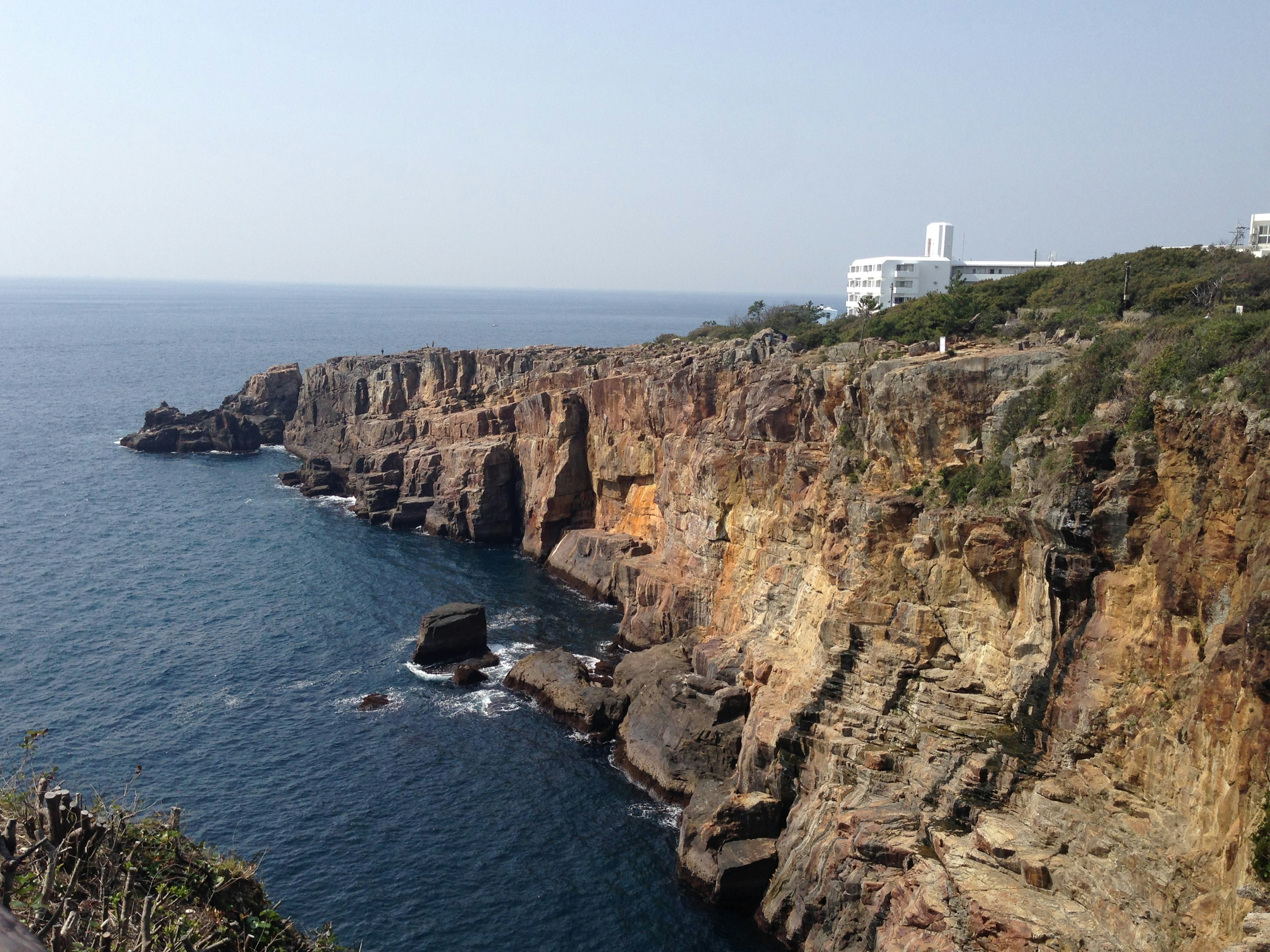 海に面した岩の崖と近くの建物の風景