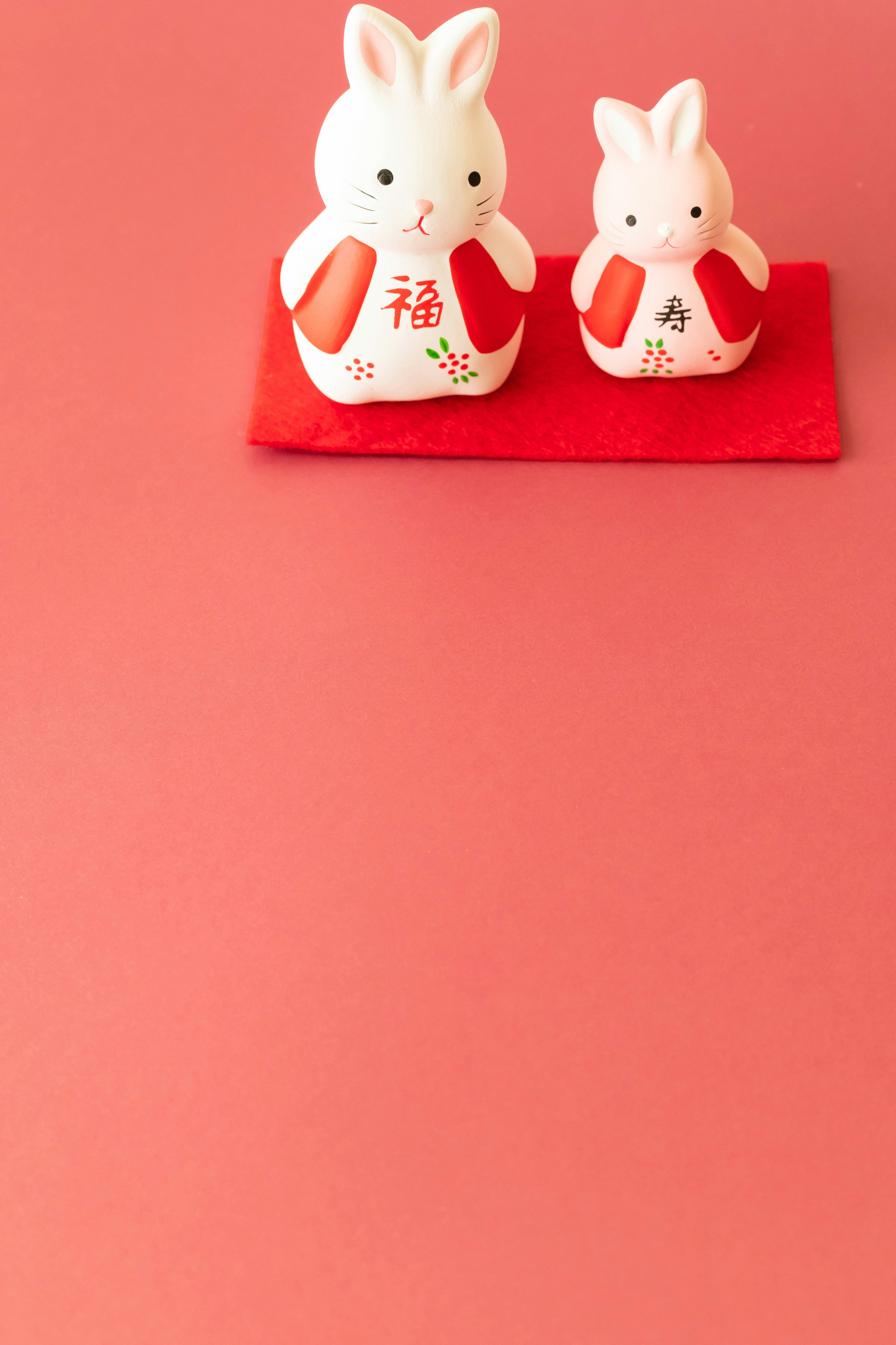 Two white rabbit figurines on a red background