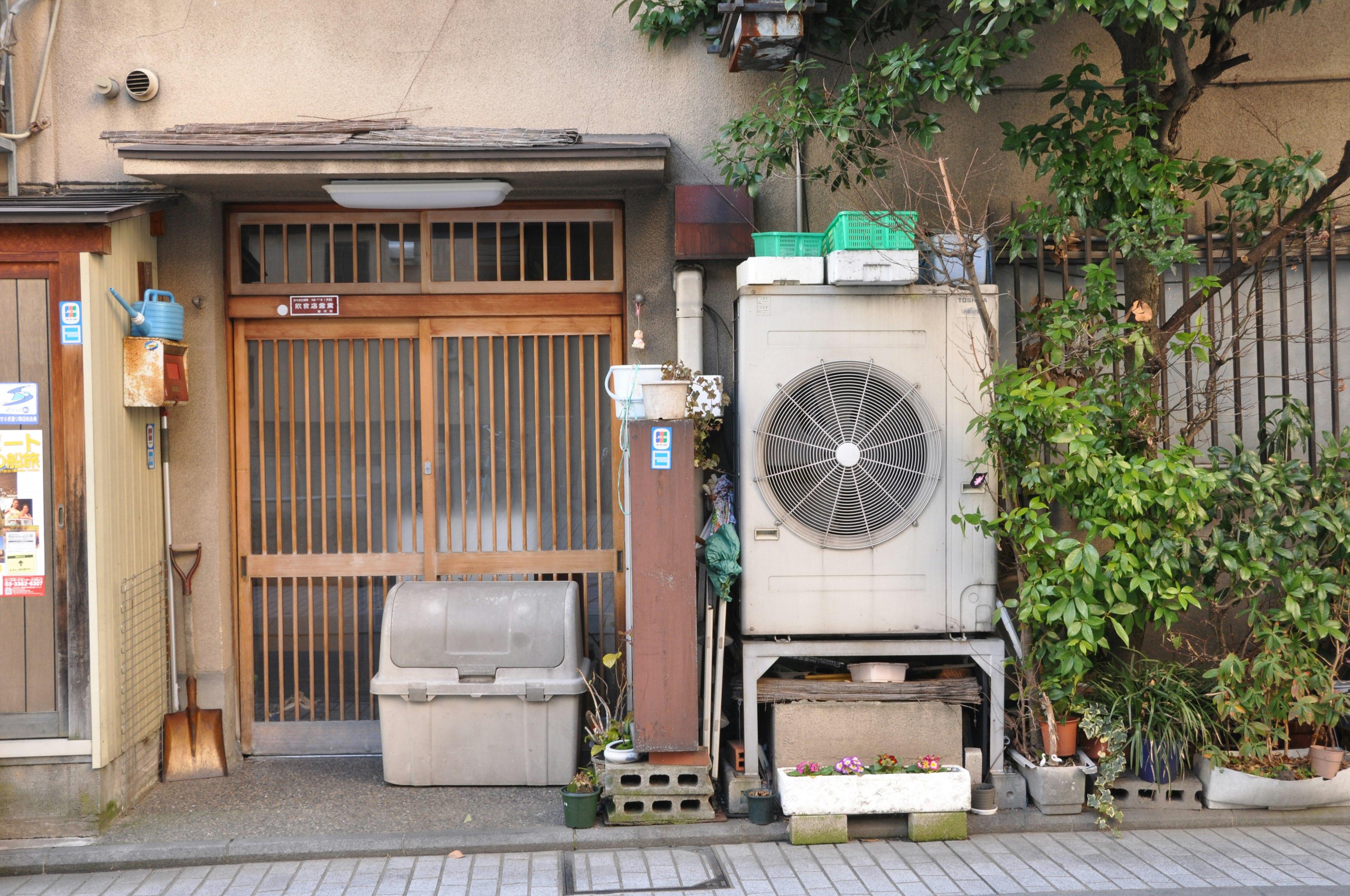 古い日本の家の入口とエアコンユニットが並ぶ風景