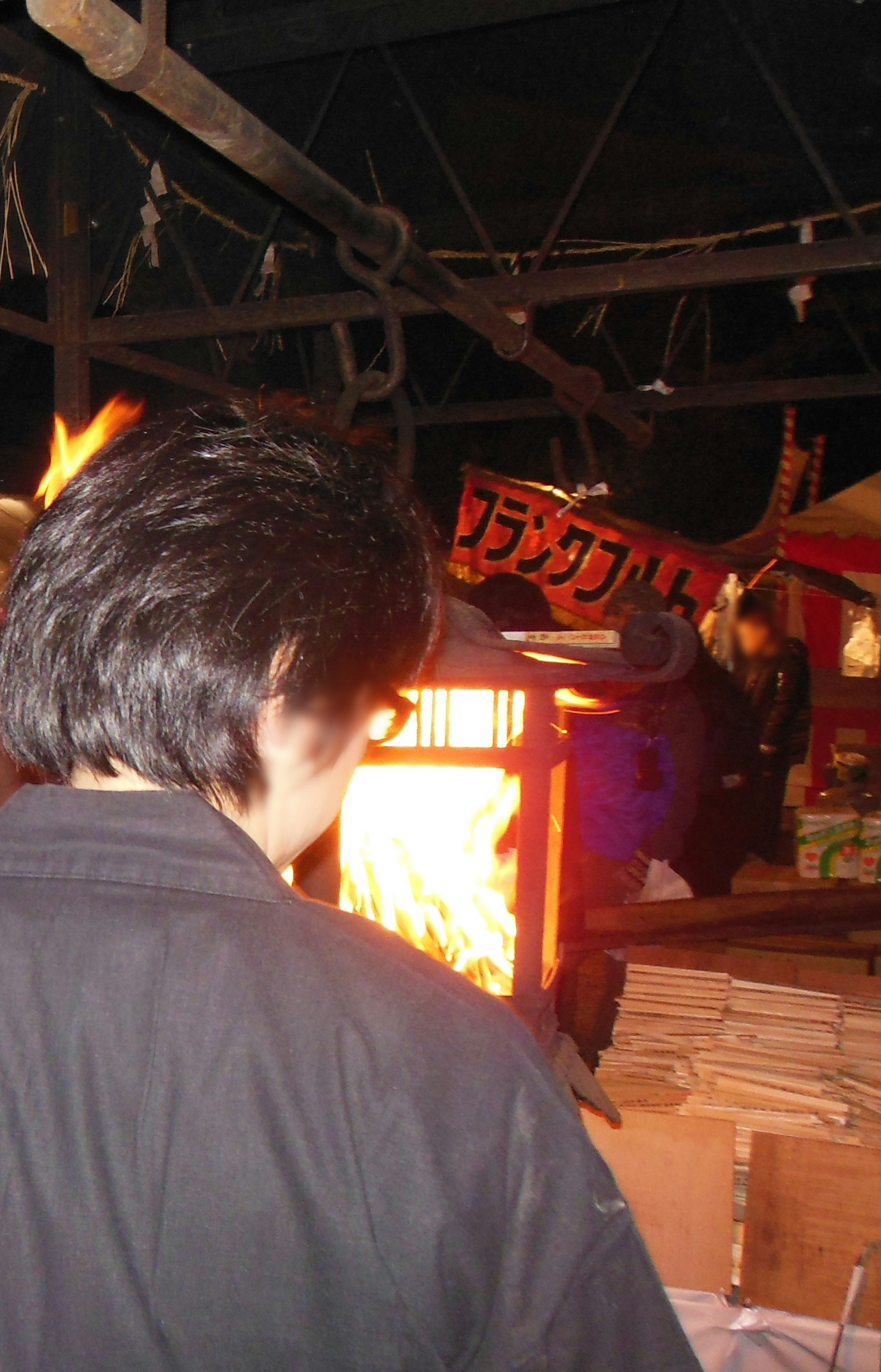 Un hombre de pie frente a un fuego en una escena de mercado al aire libre