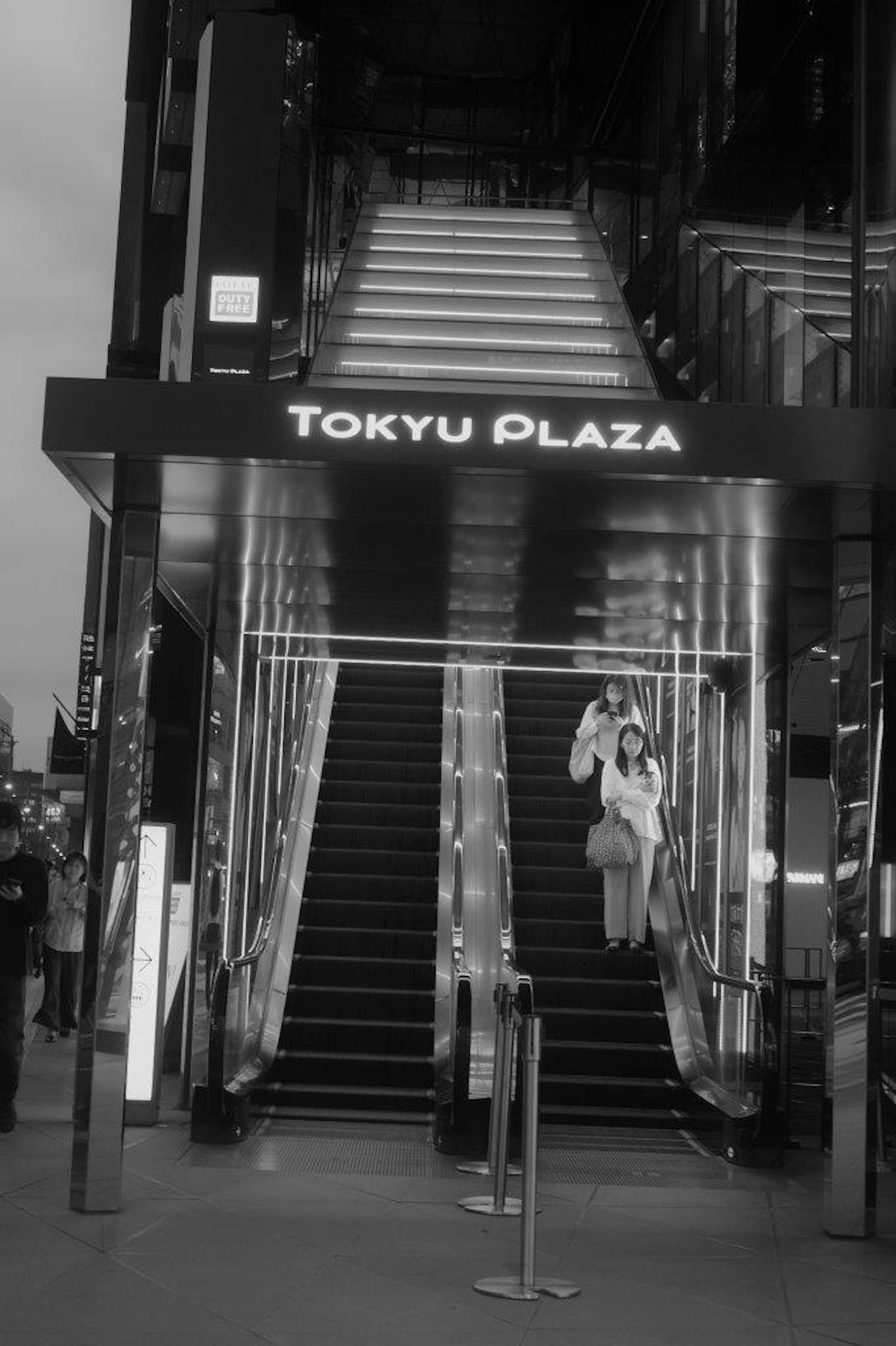 ภาพขาวดำของบันไดที่ Tokyu Plaza พร้อมกับคนหนึ่งคน