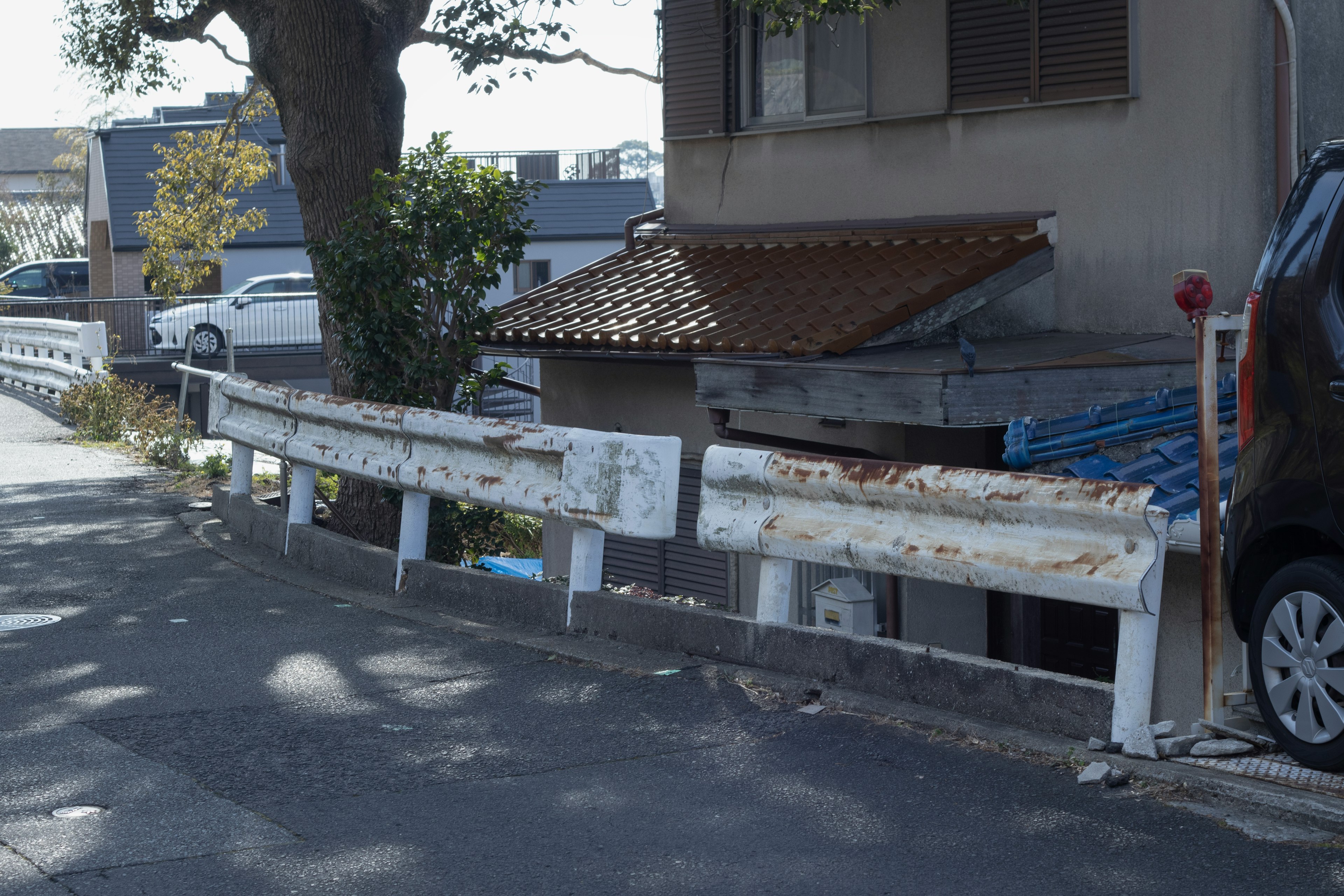 Alter weißer Schutzzaun entlang der Straße mit einem Teil eines Hauses