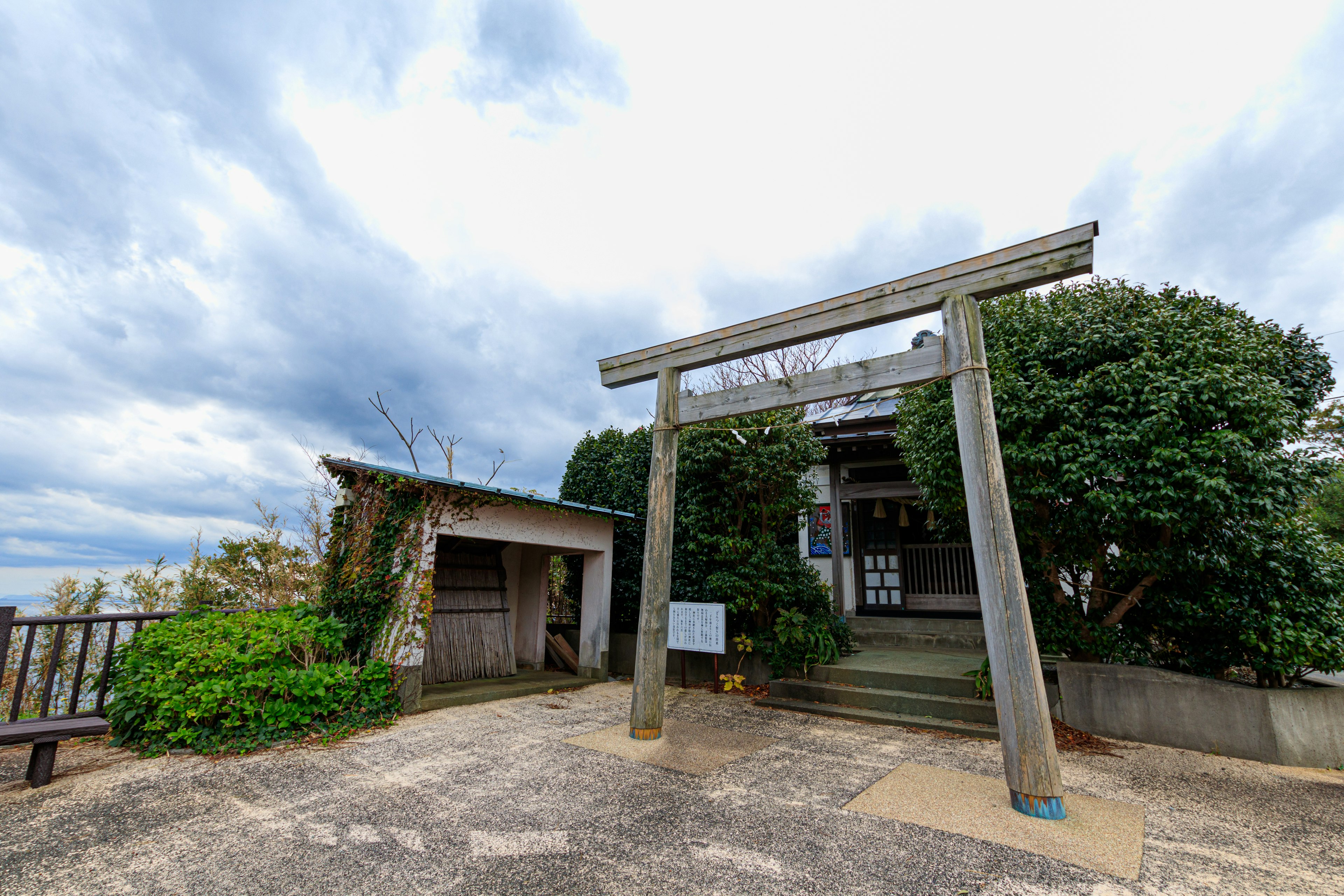 一個鳥居和綠色植物以及多雲的天空