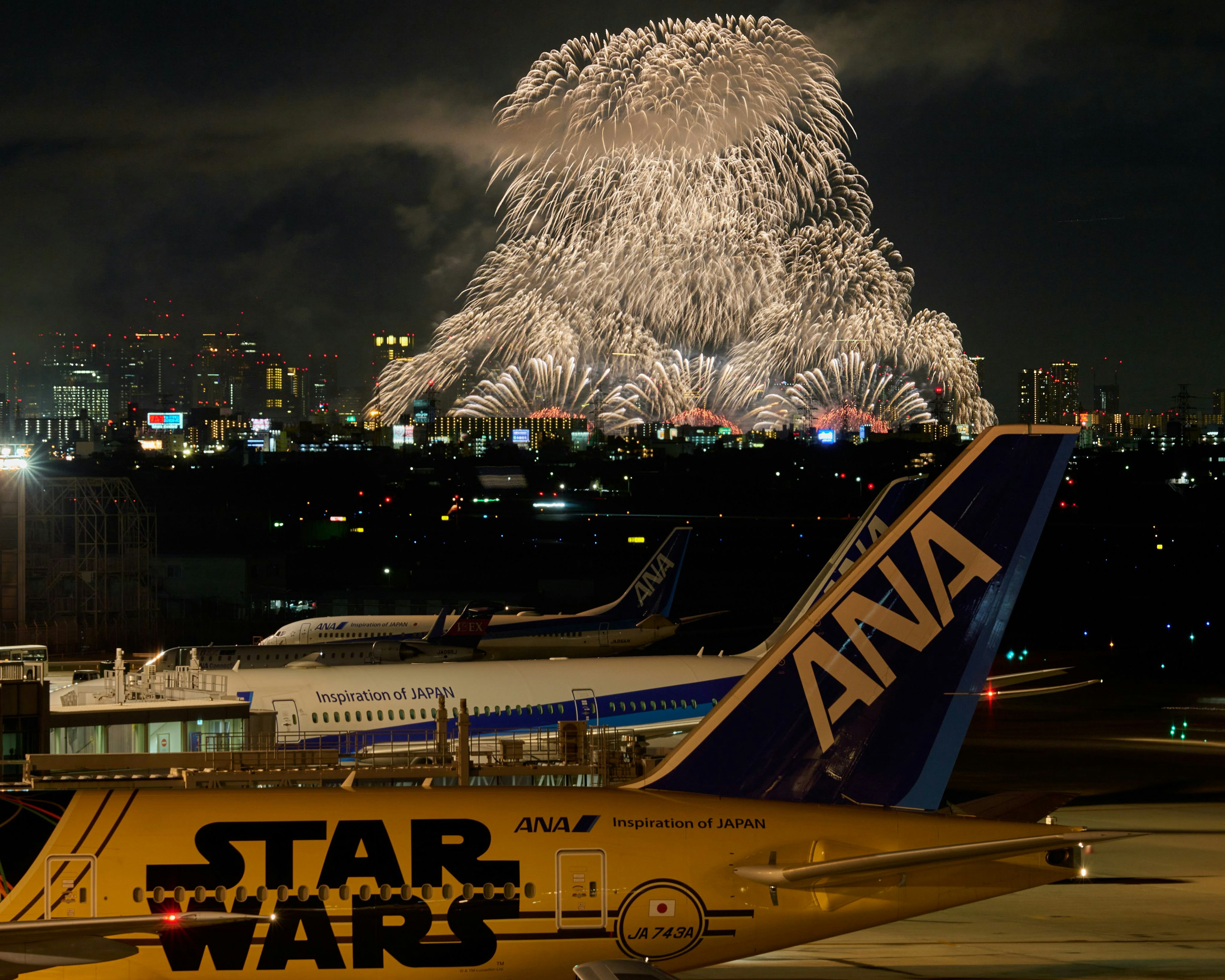 夜空に広がる花火とANA航空機の後ろに見えるスター・ウォーズのデザイン