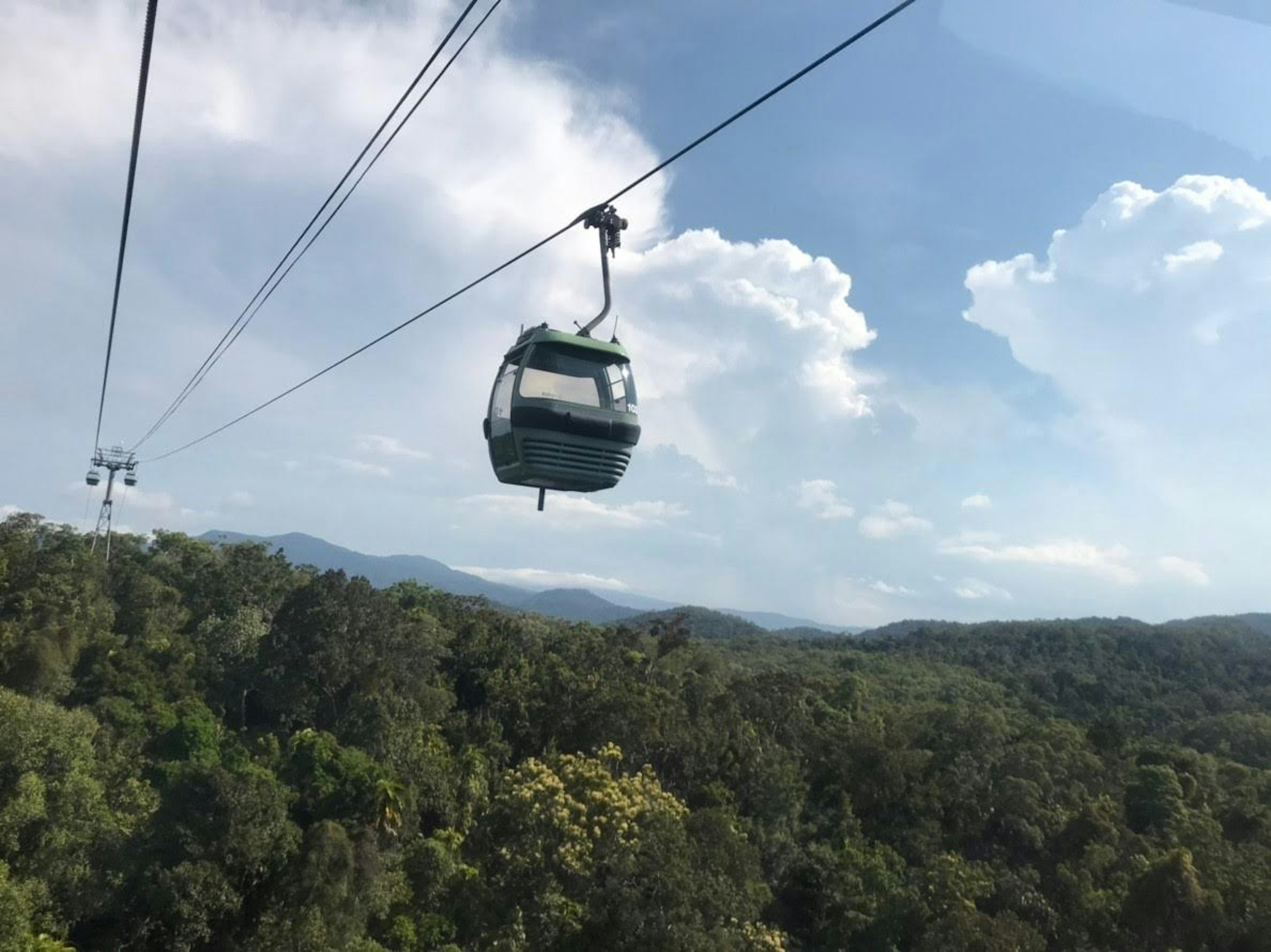 Scenic view of a cable car over lush green mountains