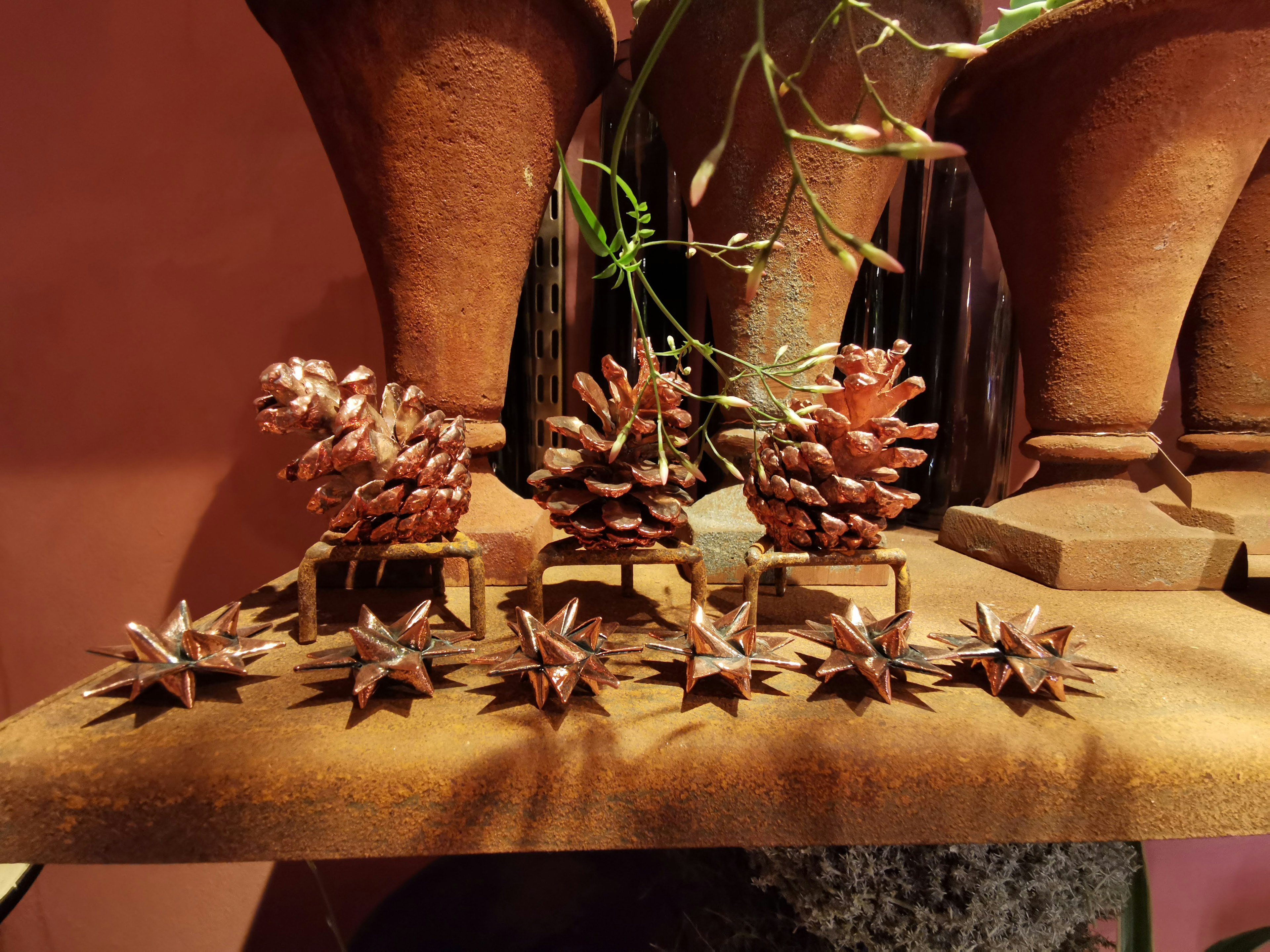 Pinecones and star-shaped objects displayed on a wooden shelf with pottery