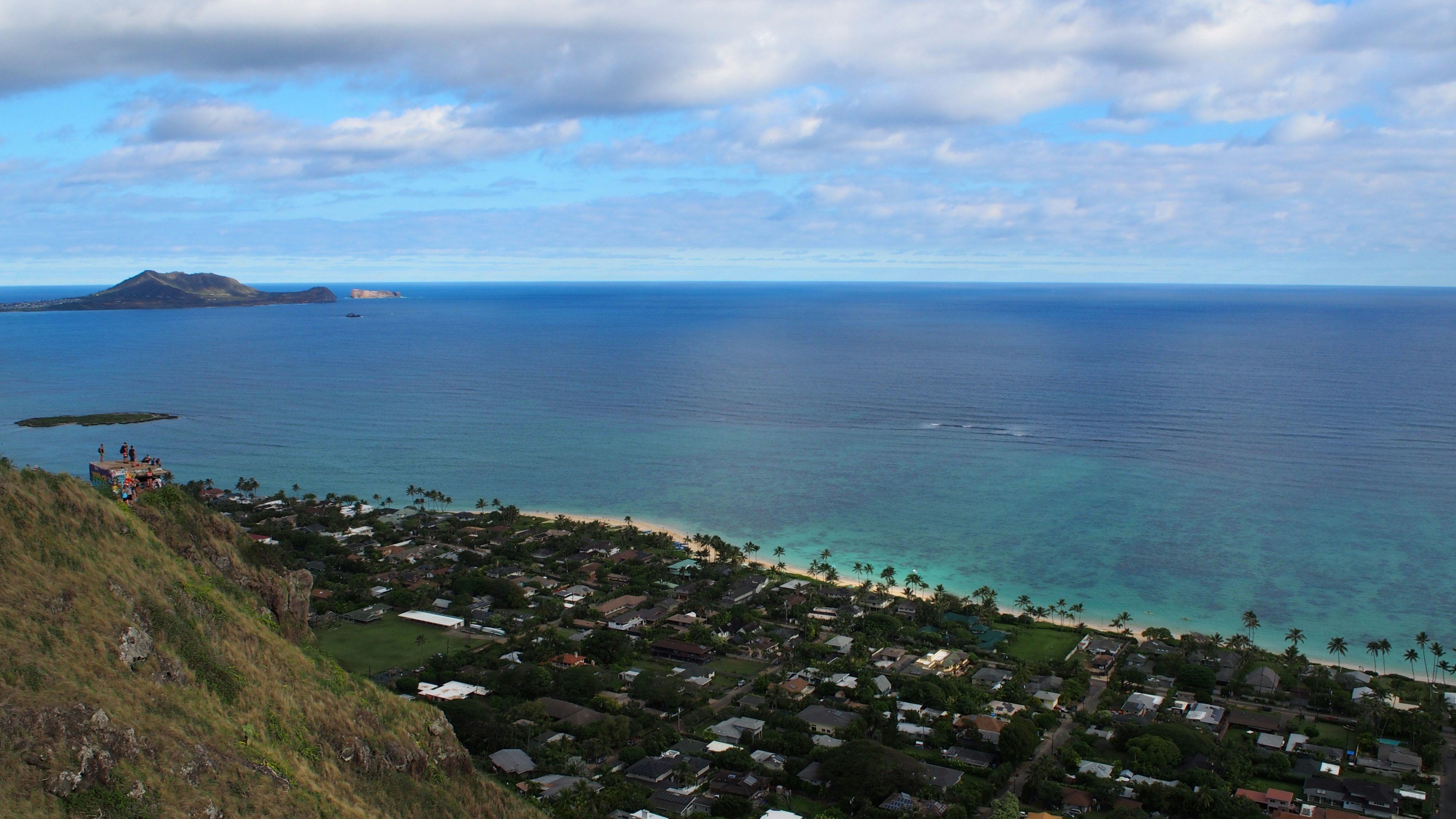 Vue panoramique sur l'océan bleu et la plage de sable blanc avec des maisons à proximité