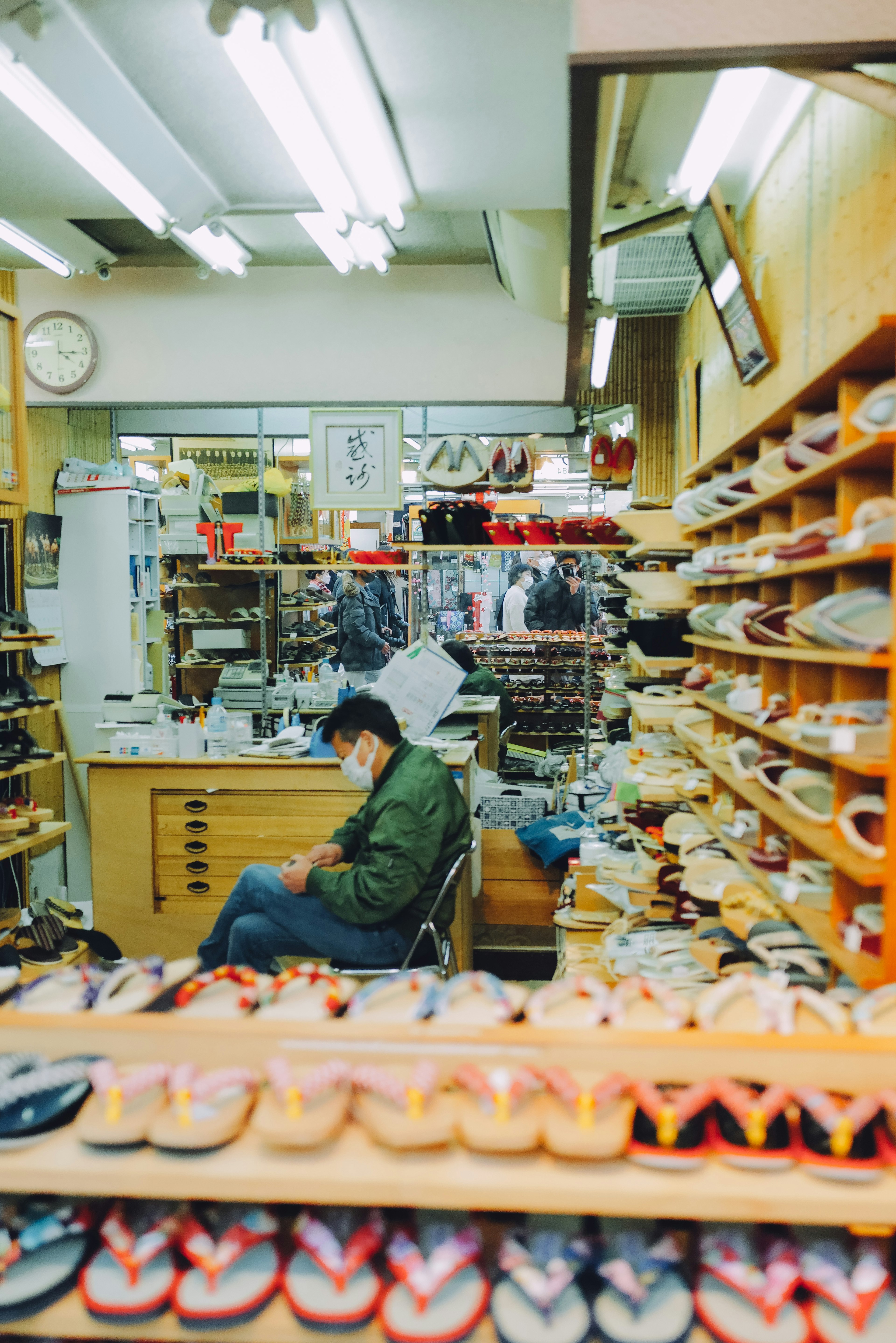 Interior de una zapatería con un hombre sentado y estantes de zapatos