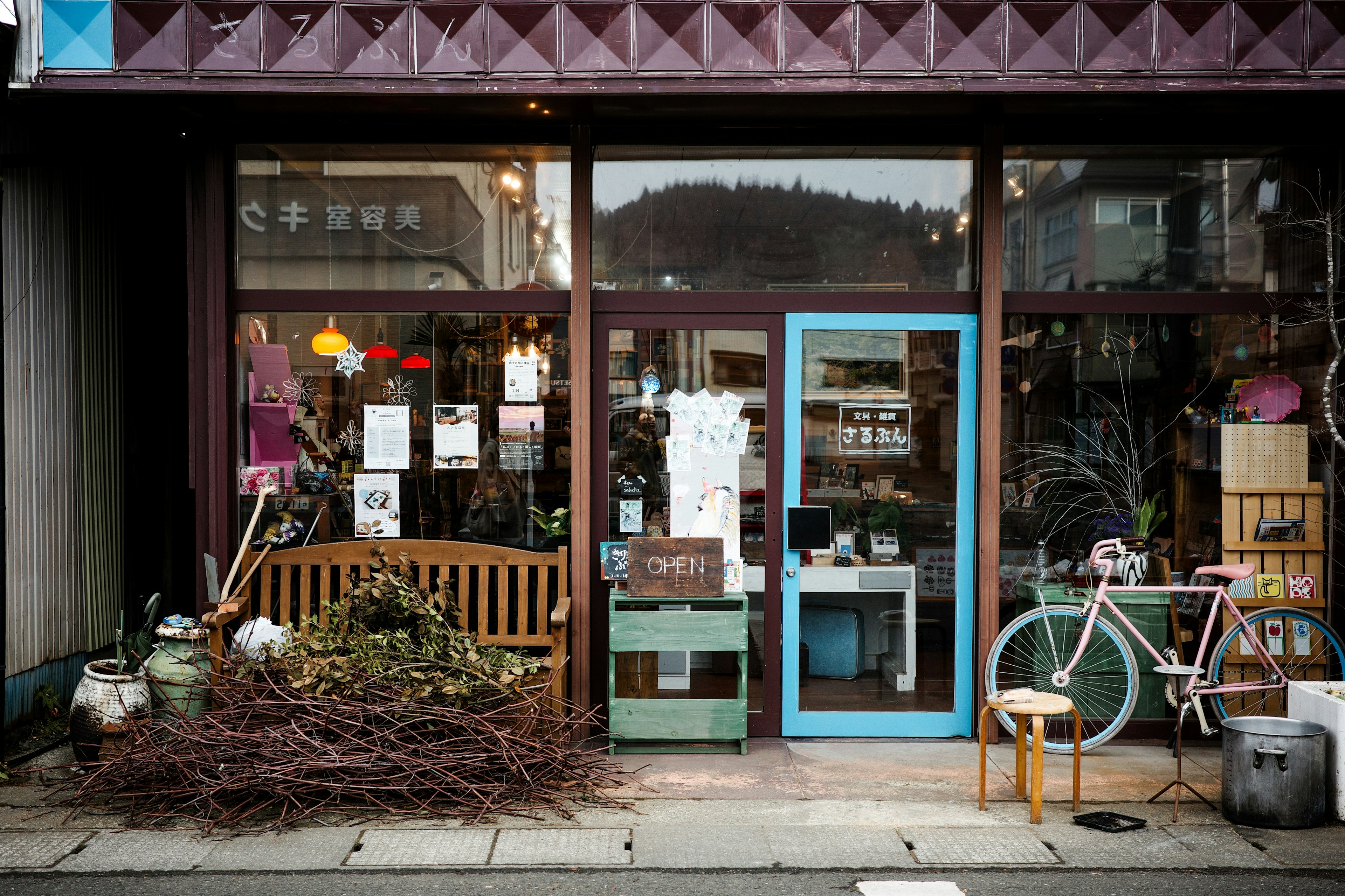 Charming storefront of a small shop with colorful decorations featuring a wooden bench and a bicycle