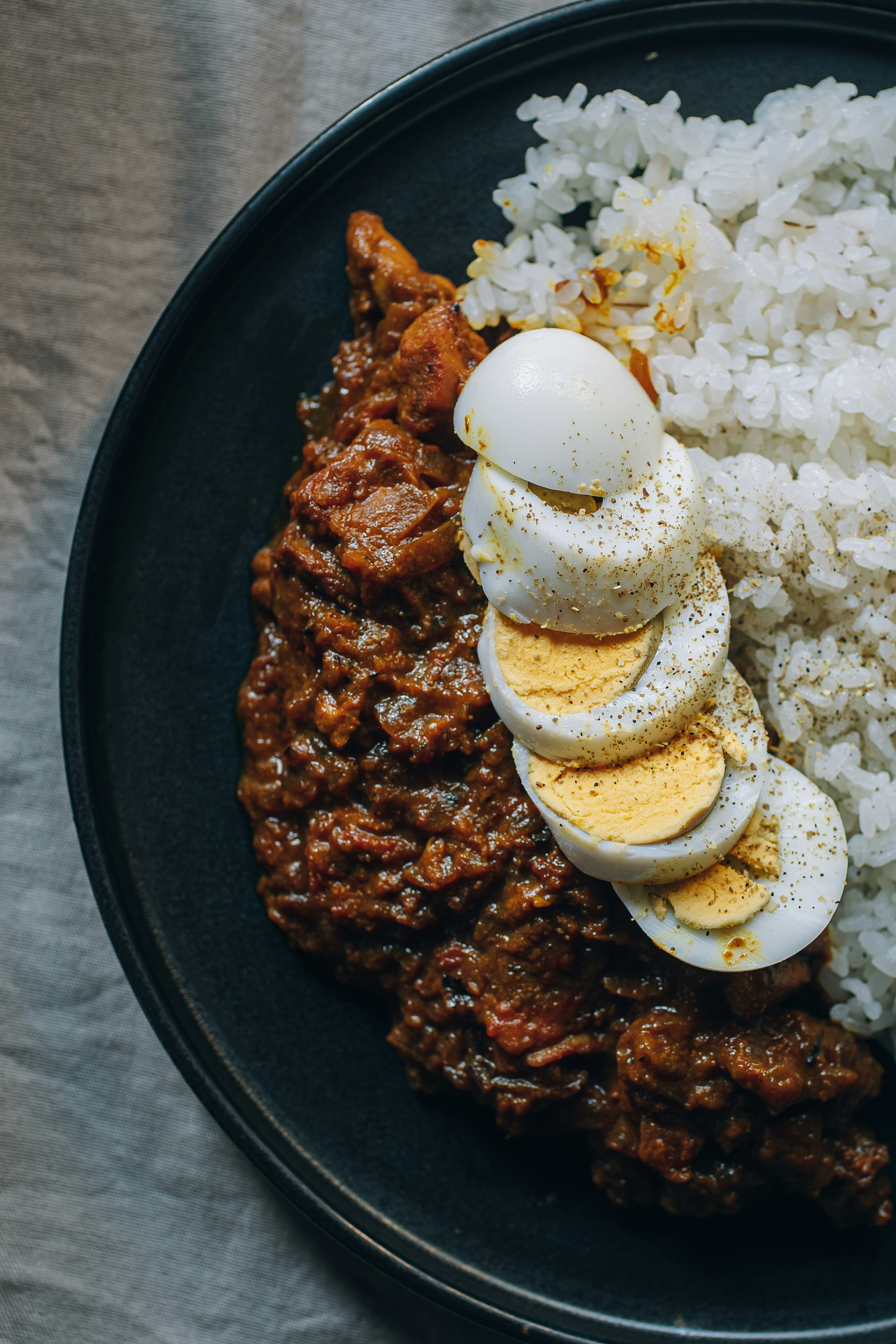 Plat avec du riz et des tranches d'œufs durs dans une assiette noire