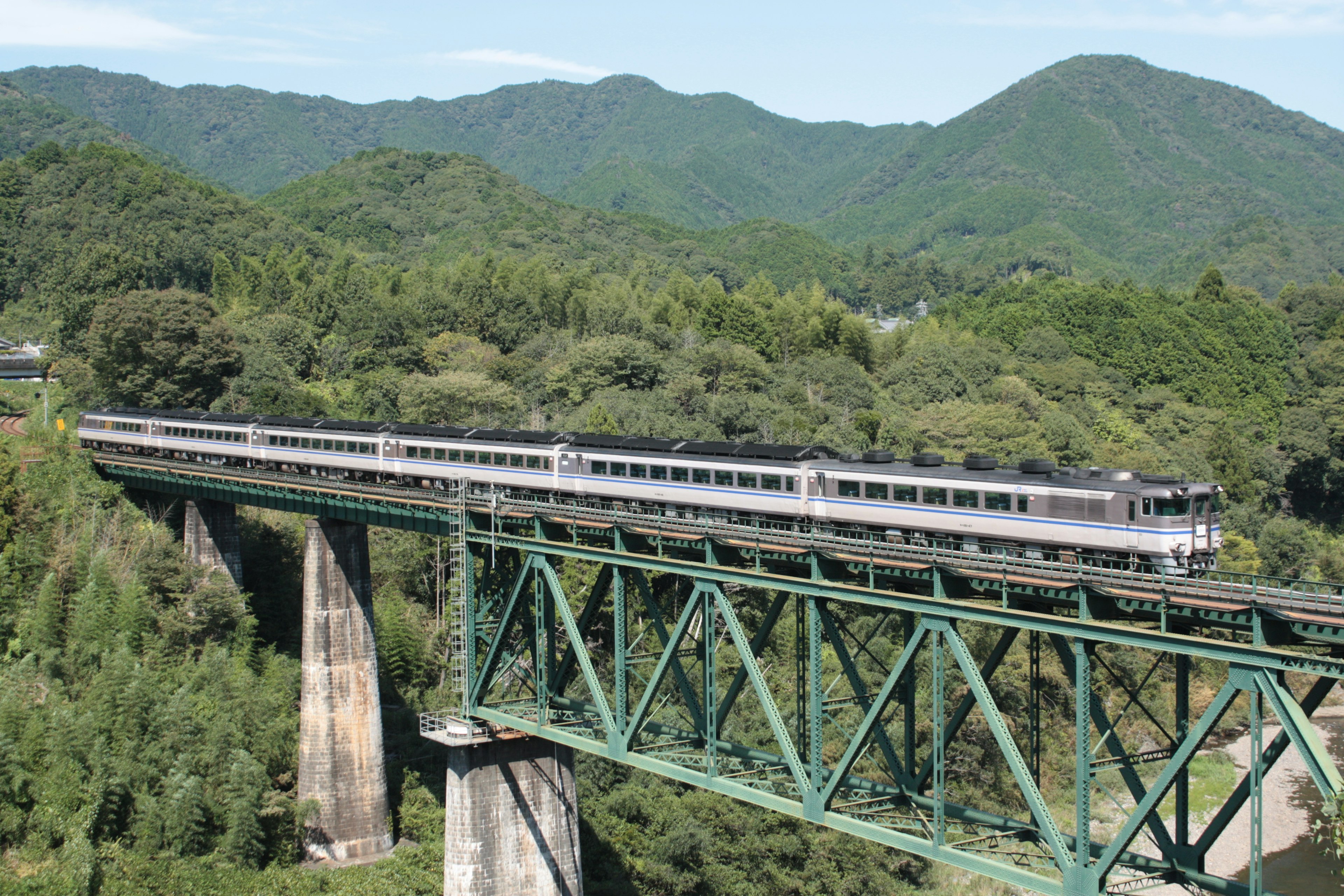 Train traversant un paysage montagneux verdoyant sur un pont