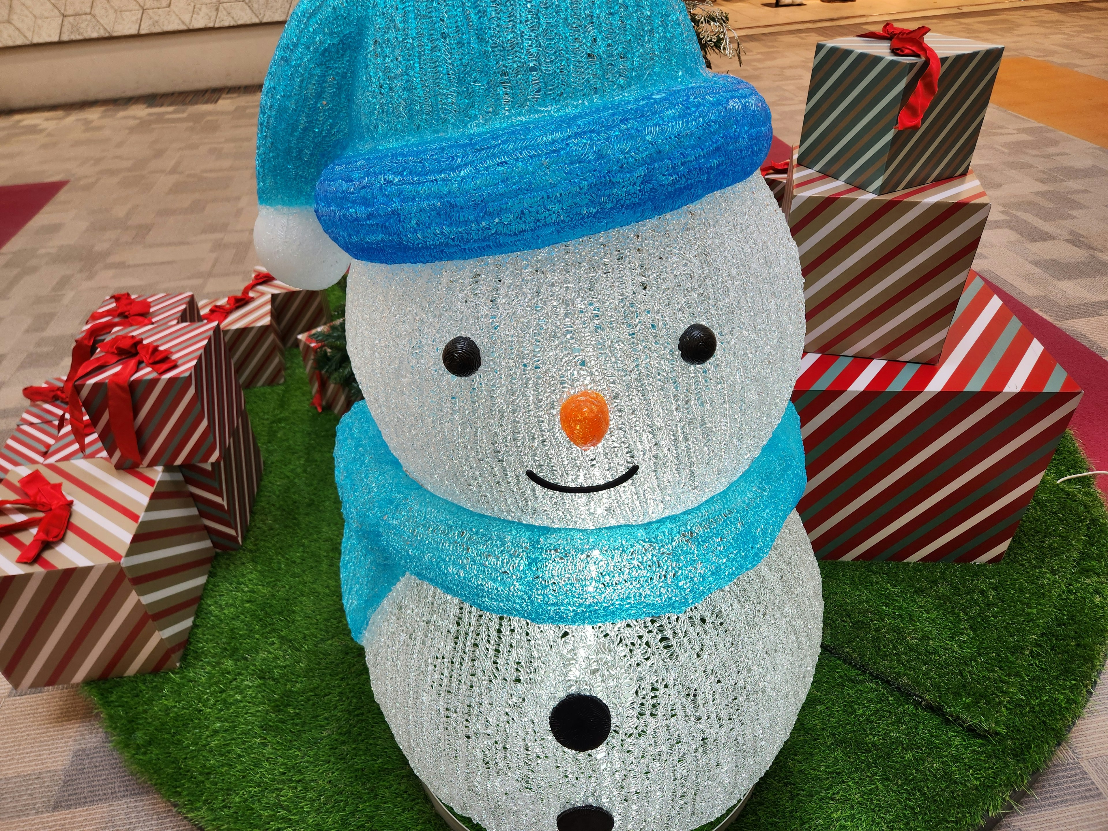 Muñeco de nieve con un sombrero azul y regalos coloridos alrededor