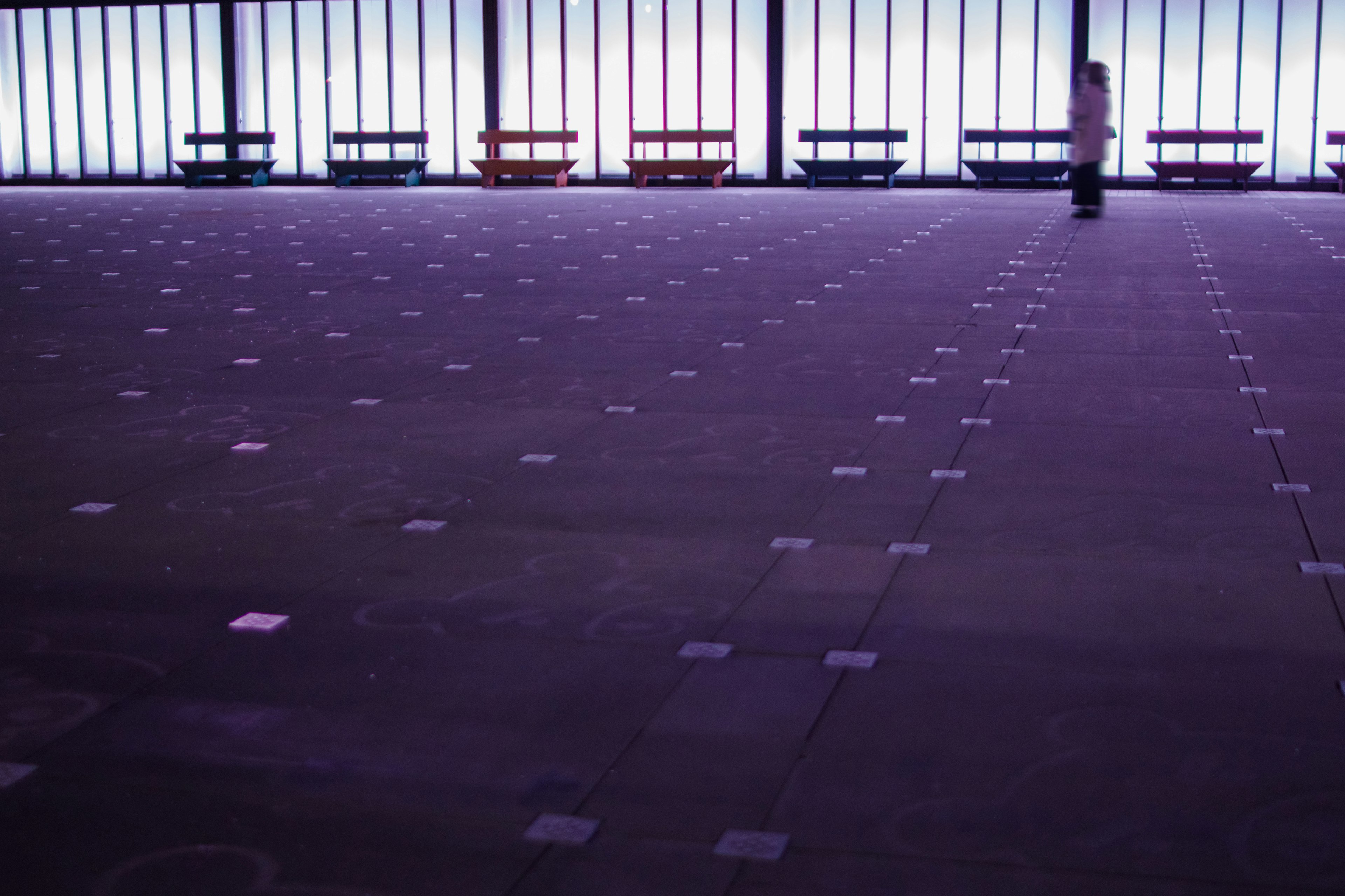 Spacious indoor area with colorful benches and a person standing