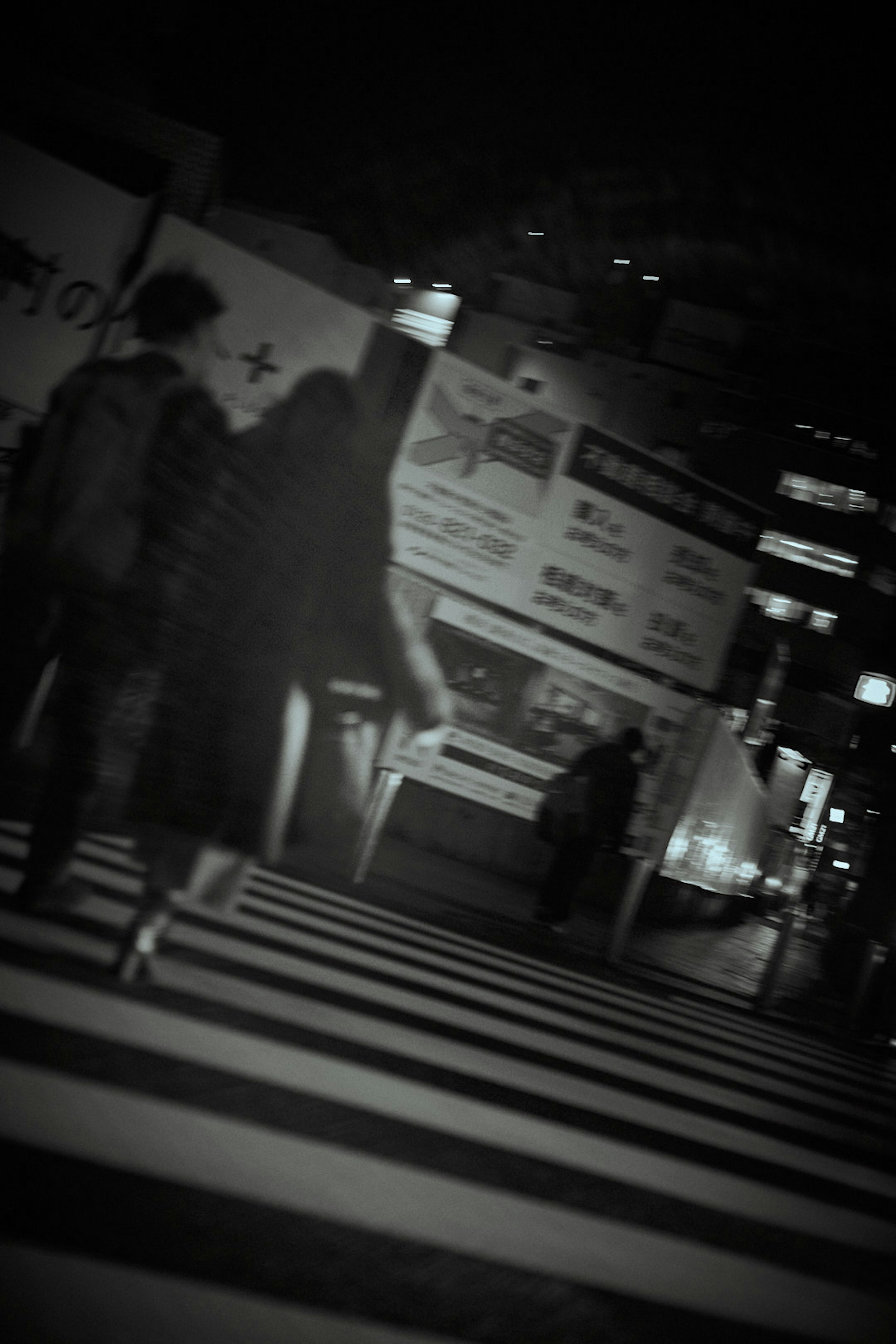 Siluetas de personas caminando en una intersección de la ciudad por la noche