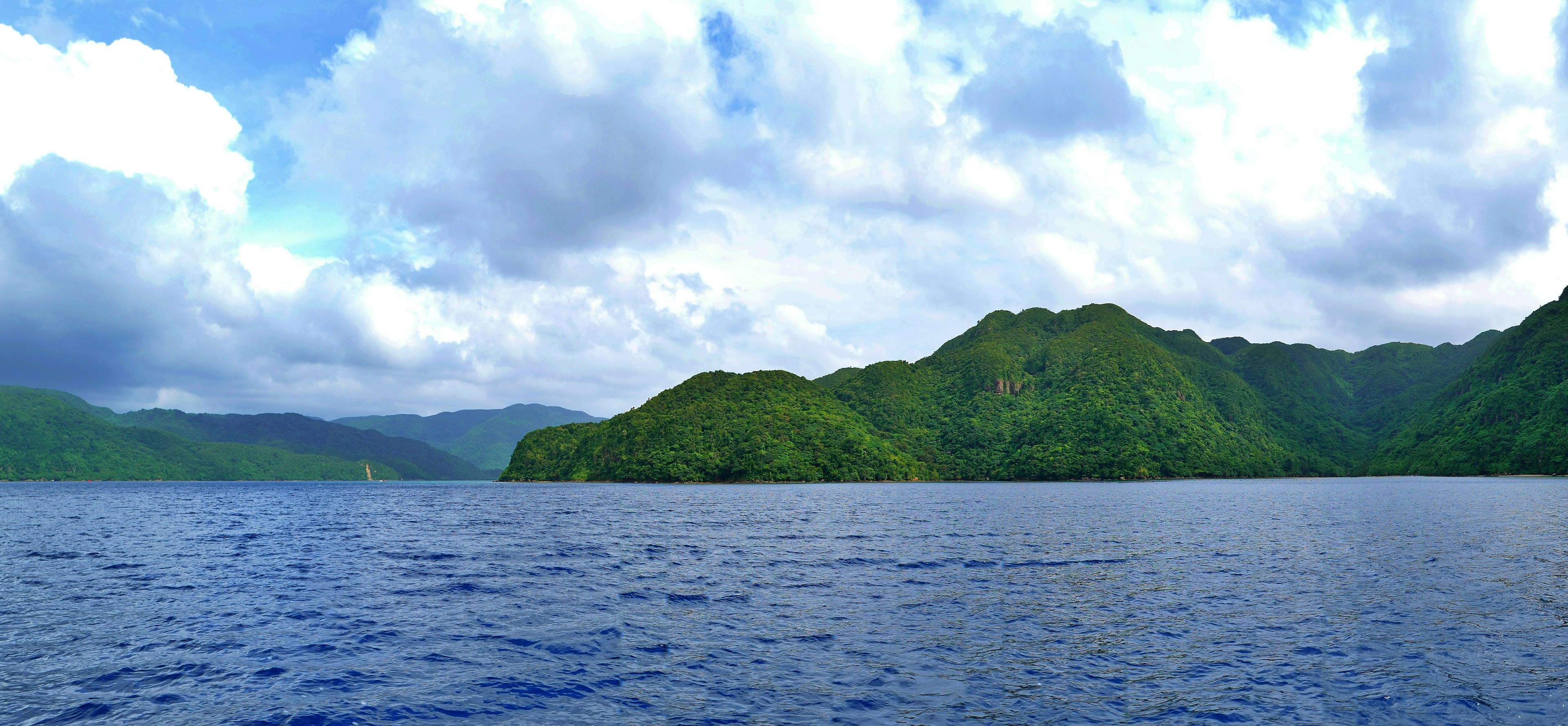 Scenic view of blue sea and lush green mountains