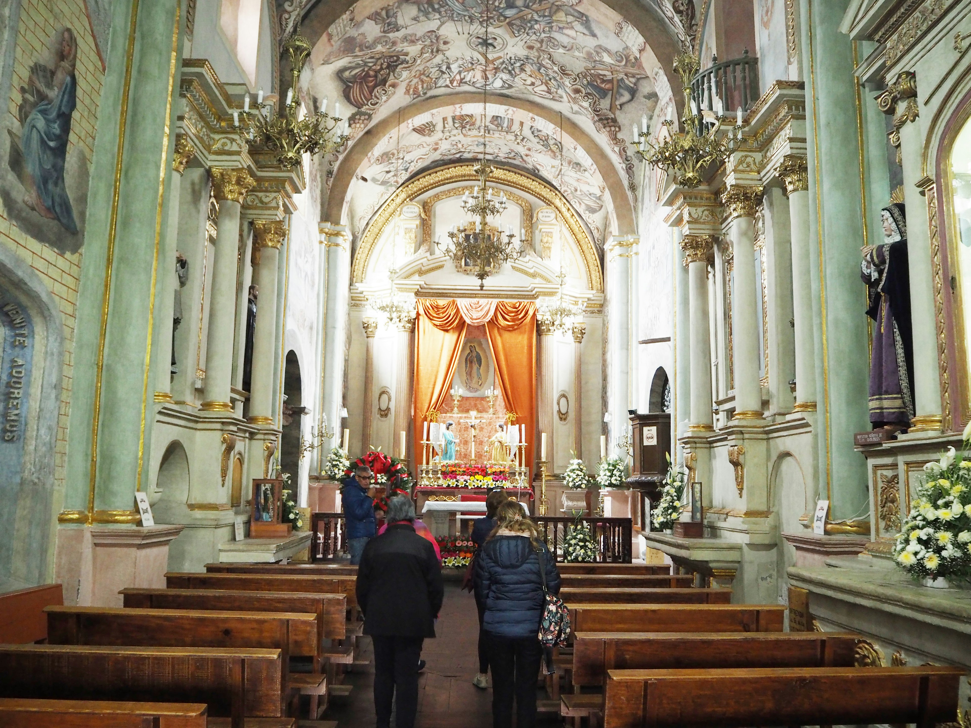 Interior of a beautiful church with intricate decor two visitors walking