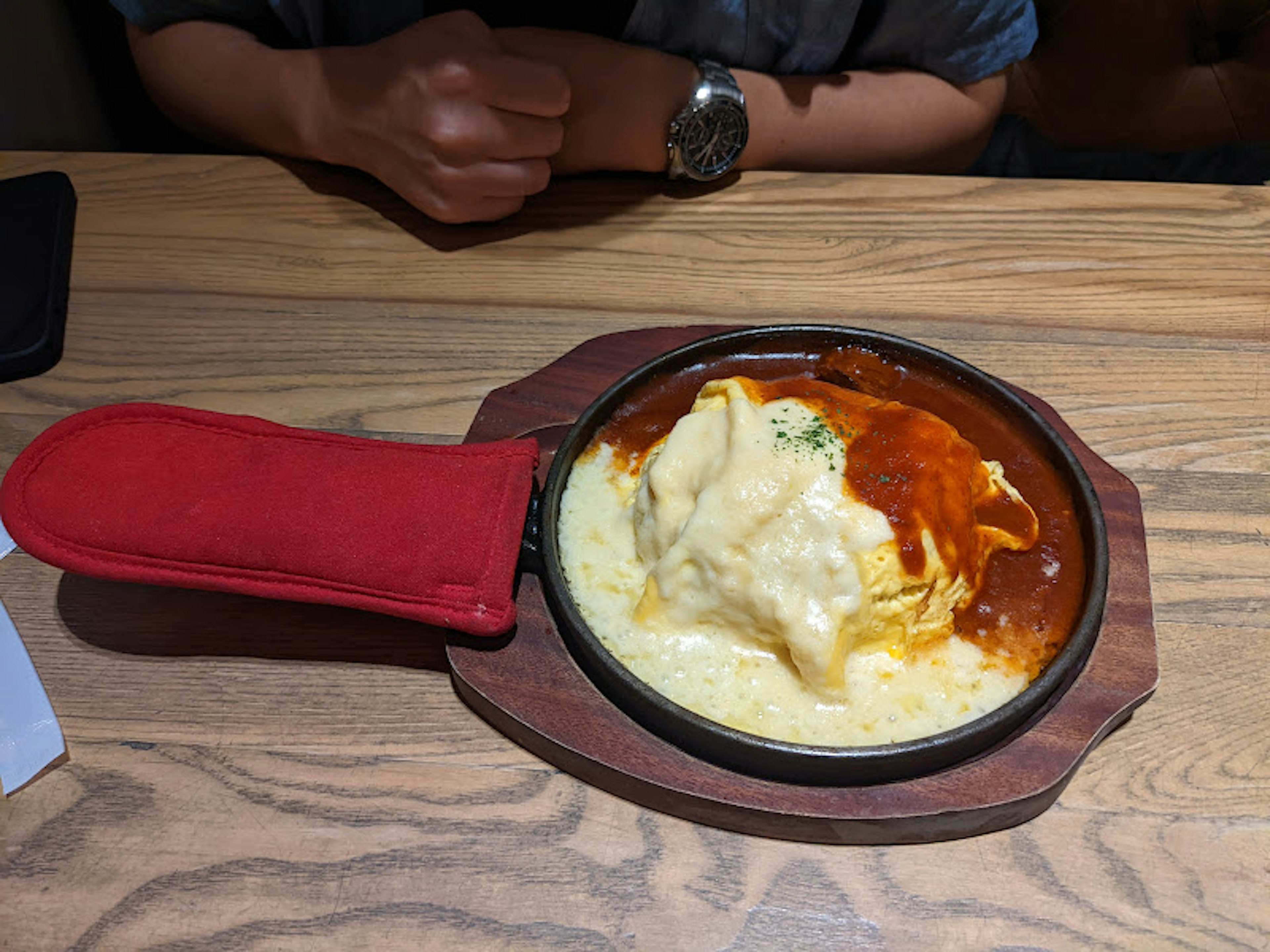 Riz omelette garni de fromage dans une poêle avec un gant rouge