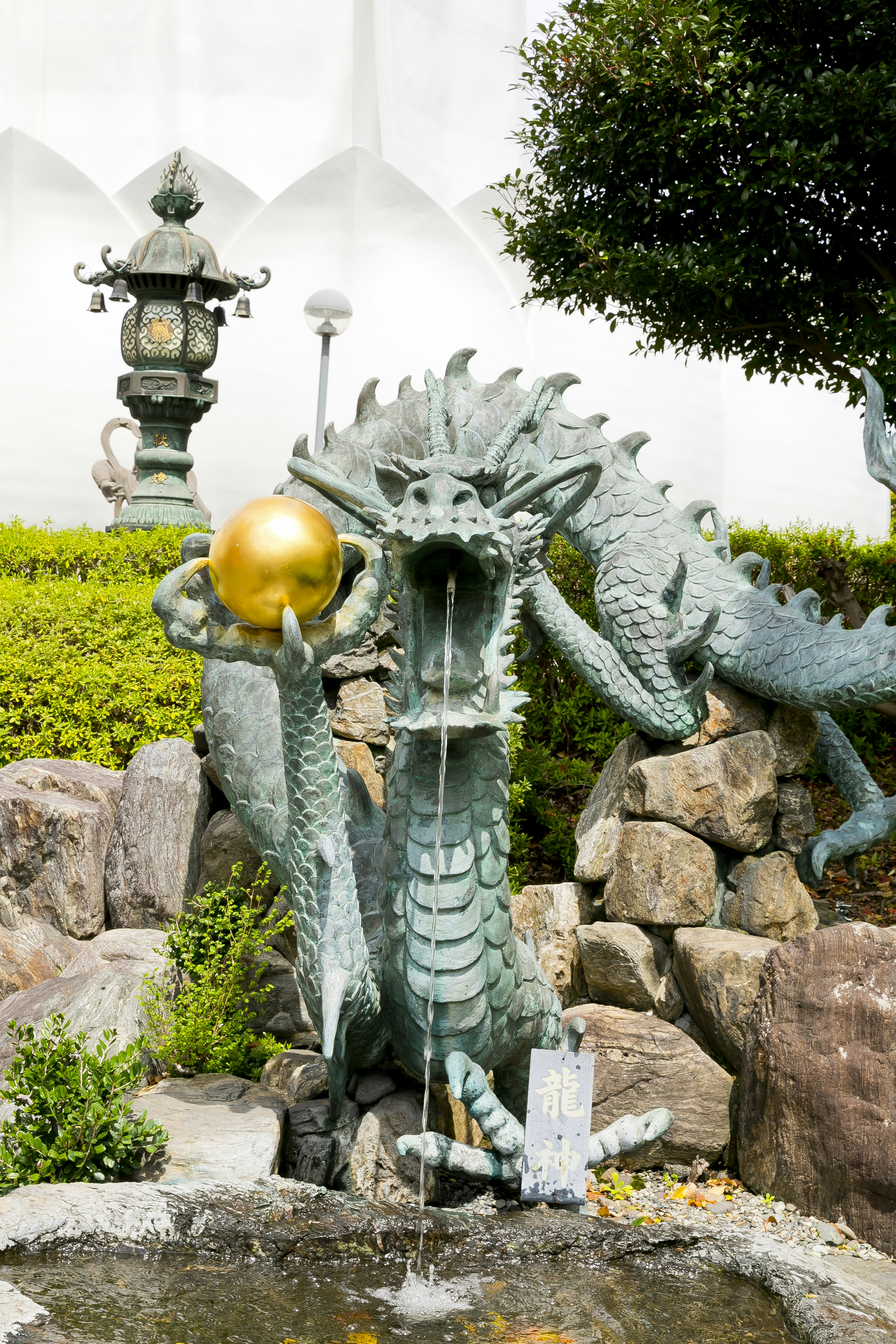 Dragon fountain holding a golden orb located in a beautiful garden