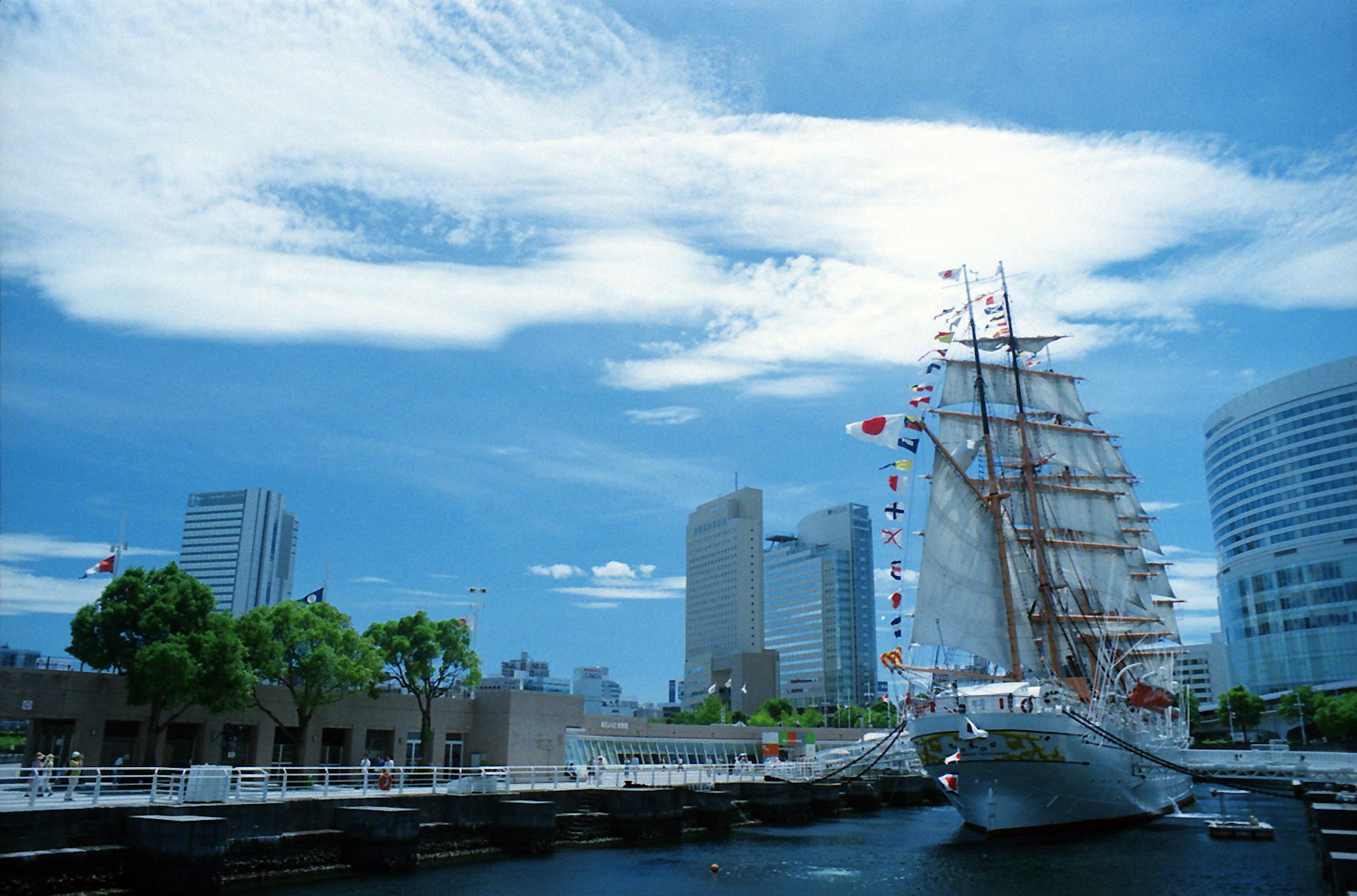 Beautiful sailing ship docked under a clear blue sky with modern buildings