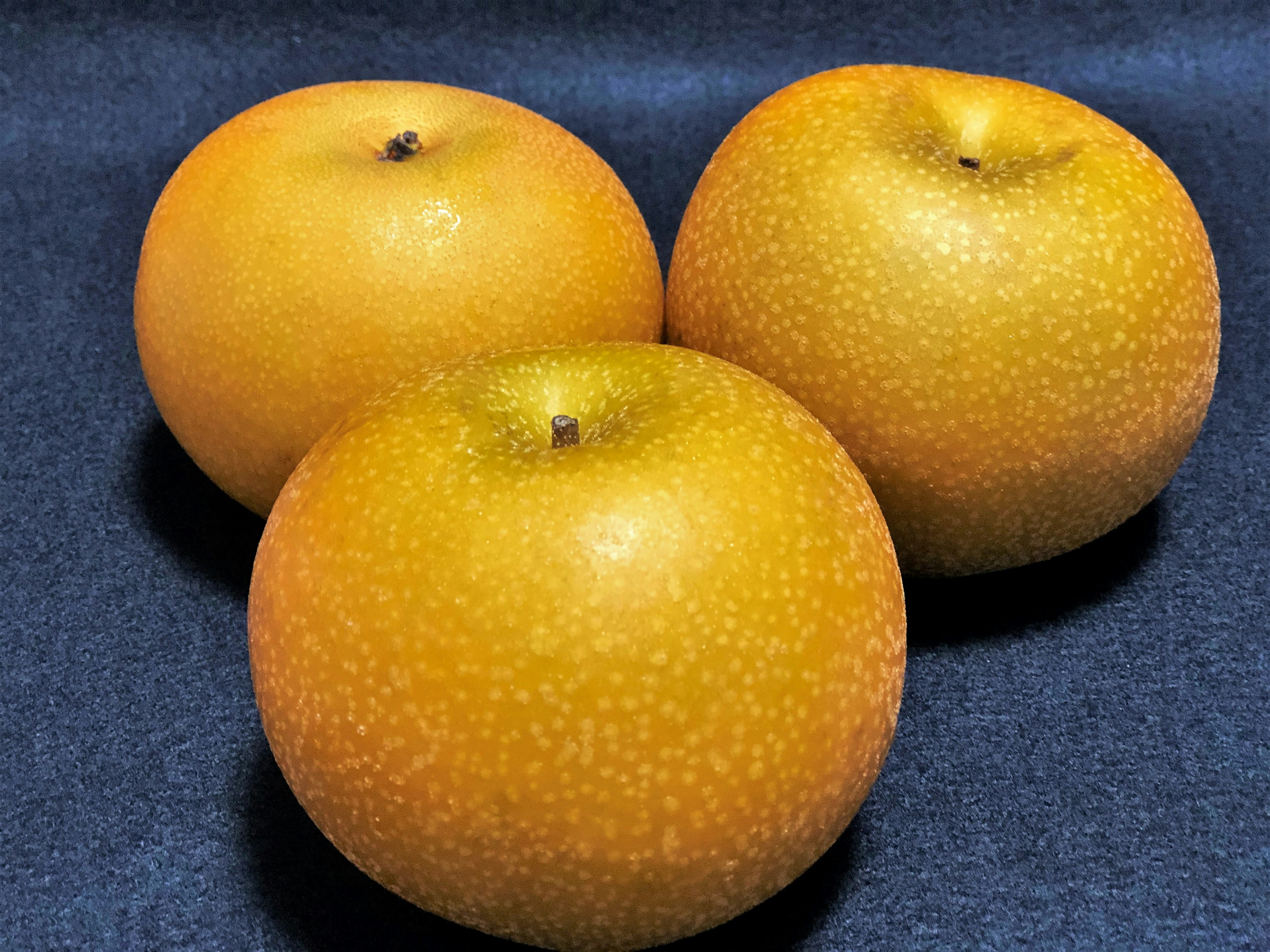 Tres frutas naranjas dispuestas sobre un fondo negro