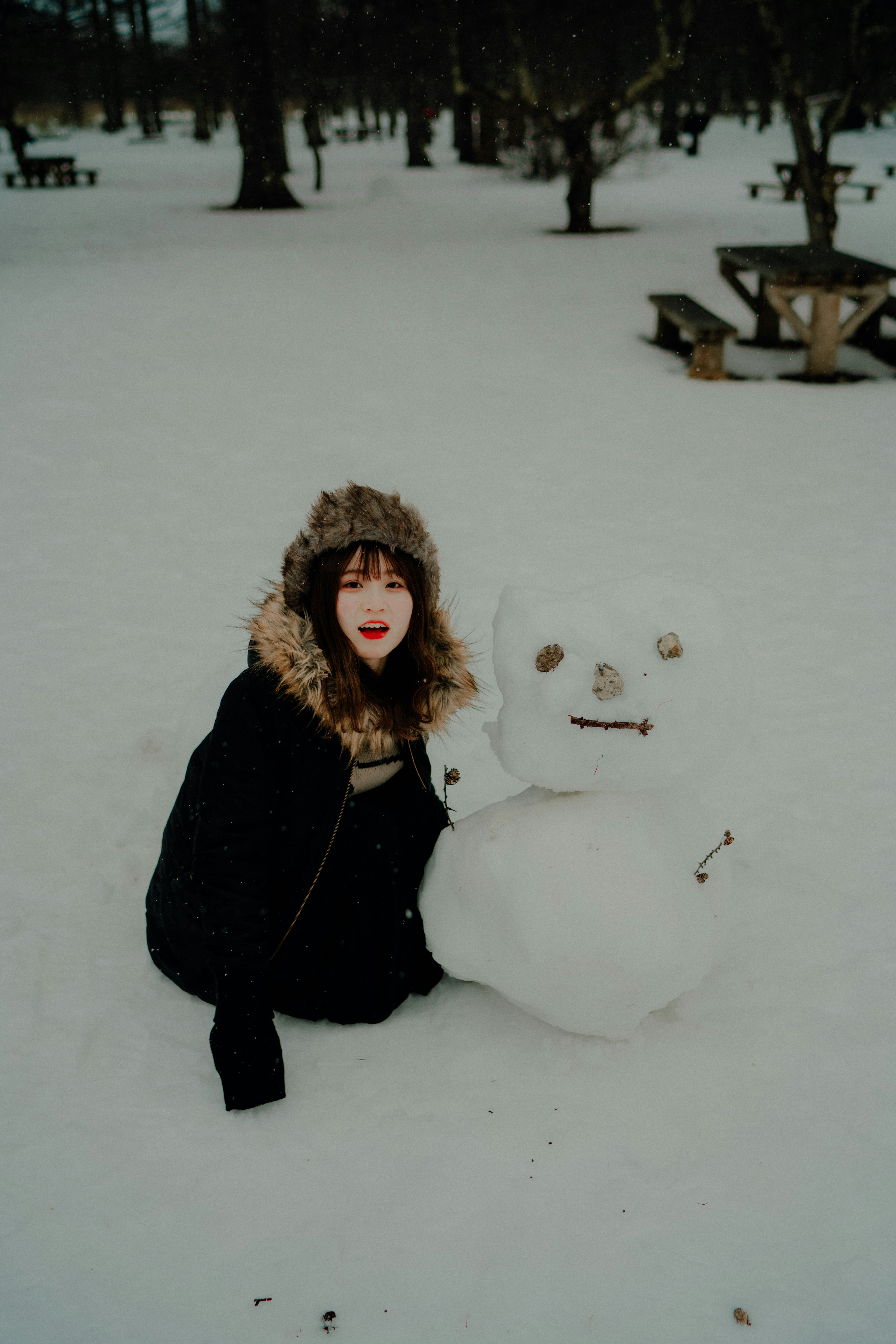 Une femme jouant avec un bonhomme de neige dans la neige